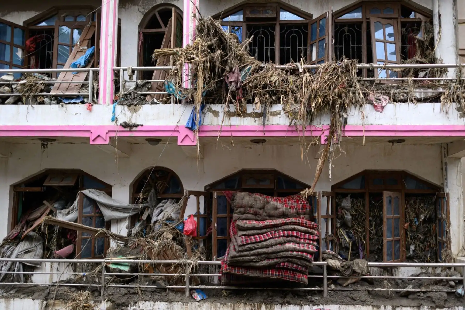 Colchones y escombros saliendo por las ventanas de una casa dañada tras las inundaciones repentinas en Devighat, en el distrito nepalí de Nuwakot. Foto: AFP