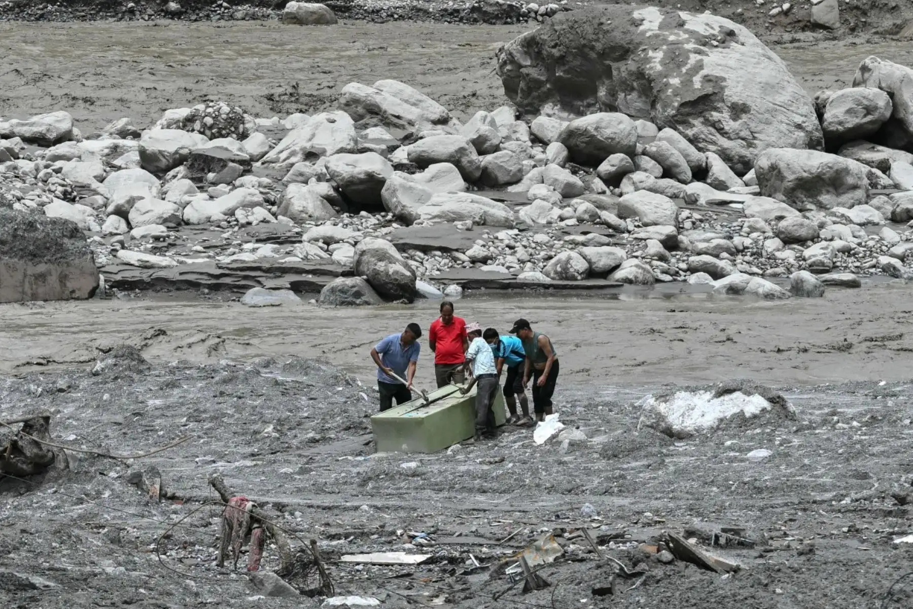 Empleados bancarios intentan abrir una caja fuerte que quedó sobre el lodo tras las repentinas inundaciones en Trishuli, en el distrito de Nuwakot (Nepal). Foto: AFP