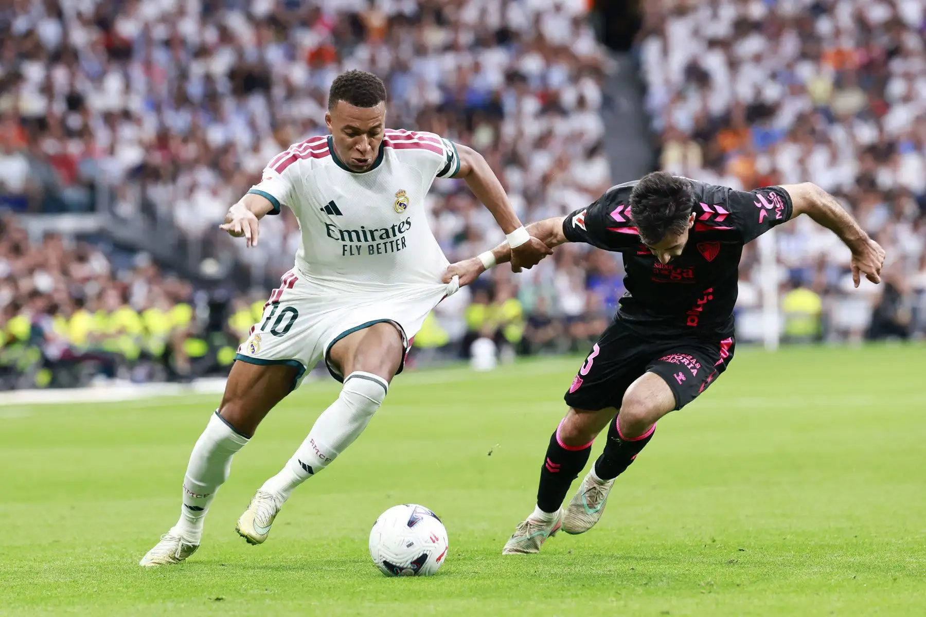 El delantero francés del Real Madrid Kylian Mbappé pelea un balón con la defensa del Málaga Carlos Puga durante el partido de LaLiga entre el Real Madrid y el Málaga, este domingo en el estadio Santiago Bernabéu.
Foto: ANDINA/ EFE
