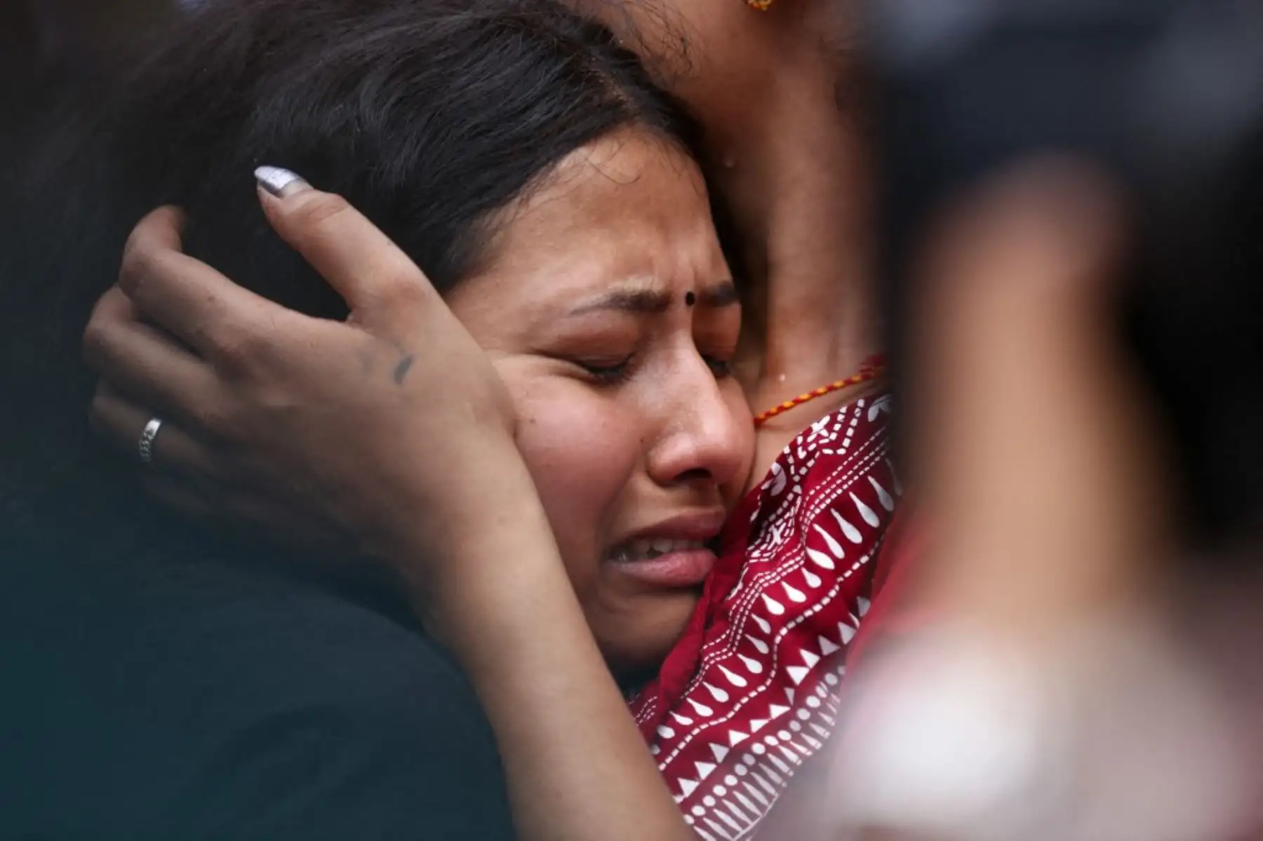 Familiares de una víctima de las inundaciones entre Tíbet y Nepal se emocionan al encontrar una foto de su ser querido colgada fuera de la morgue del Hospital Universitario Tribhuvan en Katmandú, el 30 de agosto de 2026. Foto. AFP