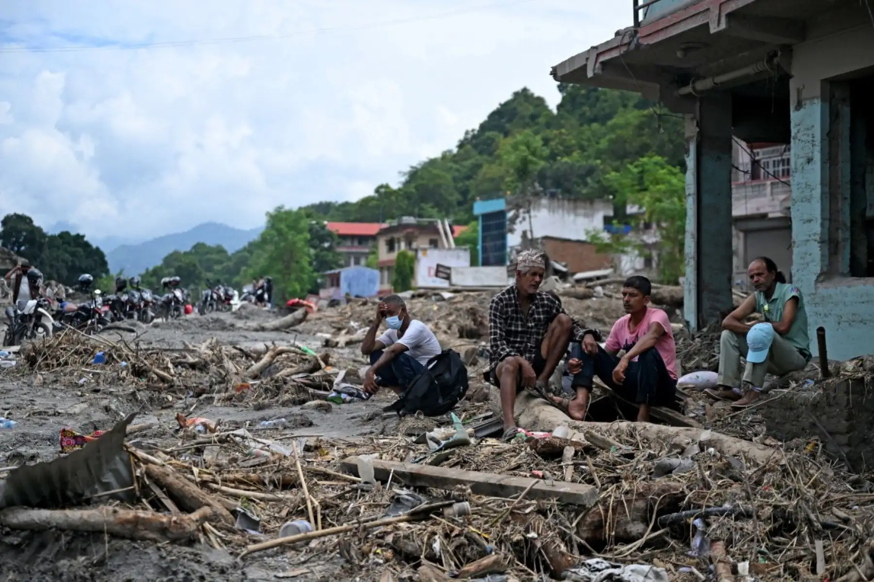Residentes se sientan junto a los escombros mientras recuperan sus pertenencias tras las inundaciones repentinas en Devighat, en el distrito nepalí de Nuwakot. Foto: AFP