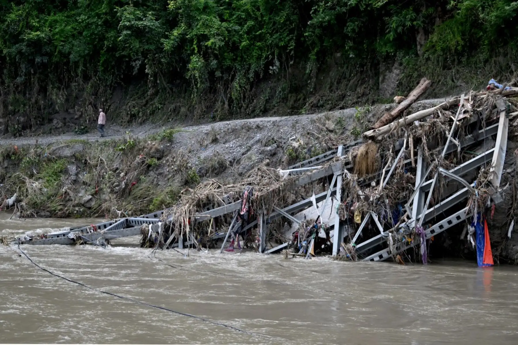 Un hombre pasa junto a un puente destruido tras unas inundaciones repentinas en Devighat, en el distrito nepalí de Nuwakot. Foto: AFP