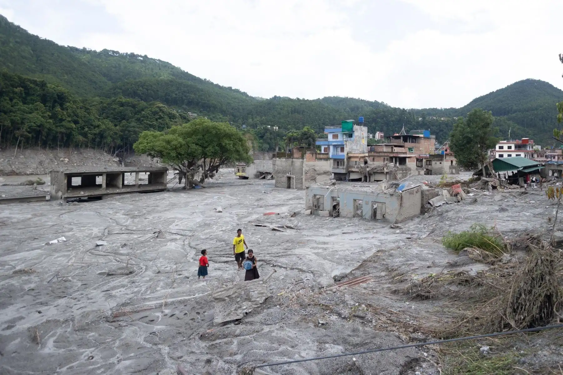 Unos niños caminan entre edificios afectados por una inundación de origen glaciar cerca de la frontera entre Nepal y China —suceso que causó cientos de muertes— en Trishuli Bazar, Nuwakot, Nepal, el 31 de agosto de 2026 (publicado el 2 de septiembre de 2026).
 Foto: EFE