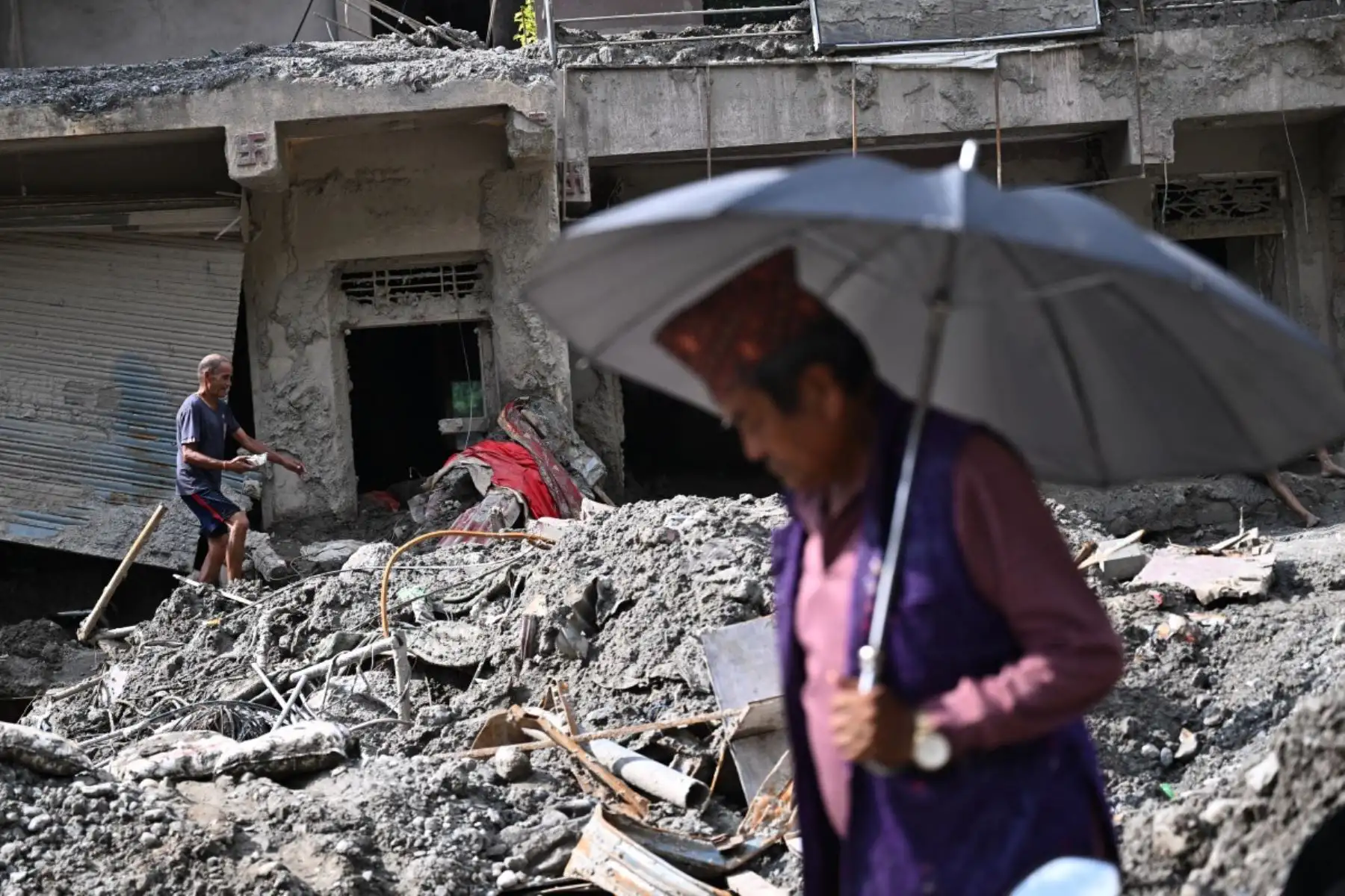 Un hombre camina junto a casas dañadas y cubiertas de lodo tras las repentinas inundaciones ocurridas en Trishuli, en el distrito nepalí de Nuwakot. Foto: AFP
