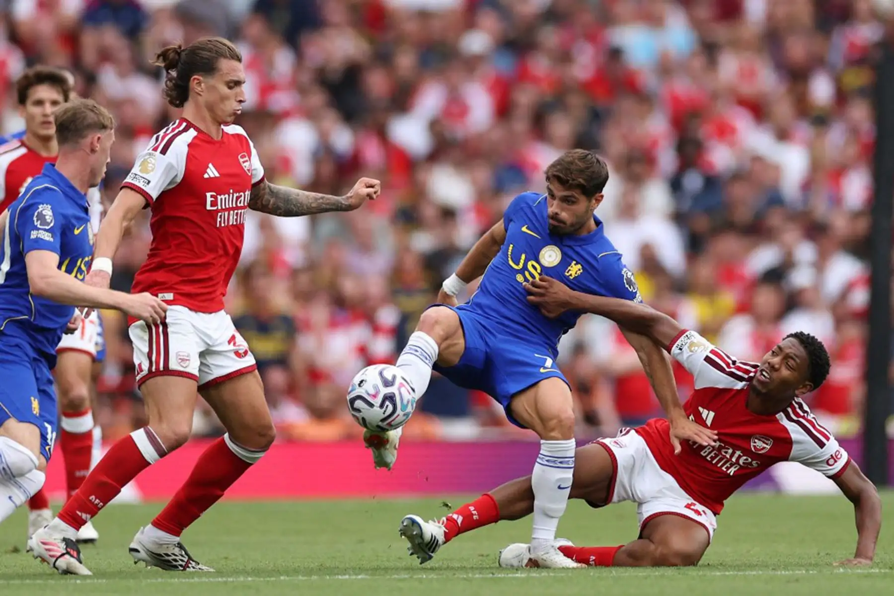 El centrocampista inglés del Arsenal, Myles Lewis-Skelly, disputa el balón con el centrocampista portugués del Chelsea, Pedro Neto y el defensa italiano del Arsenal, Riccardo Calafiori, mientras el centrocampista inglés del Chelsea, Cole Palmer, observa la acción durante el partido de la Premier League inglesa entre el Arsenal y el Chelsea en el Emirates Stadium de Londres. Foto: AFP