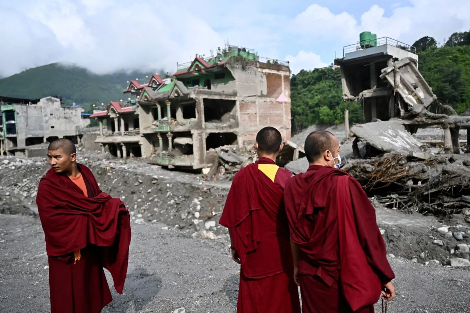 Unos monjes budistas observan los restos antes de una ceremonia en memoria de las víctimas de las inundaciones repentinas en Trishuli, en el distrito nepalí de Nuwakot. Foto: AFP