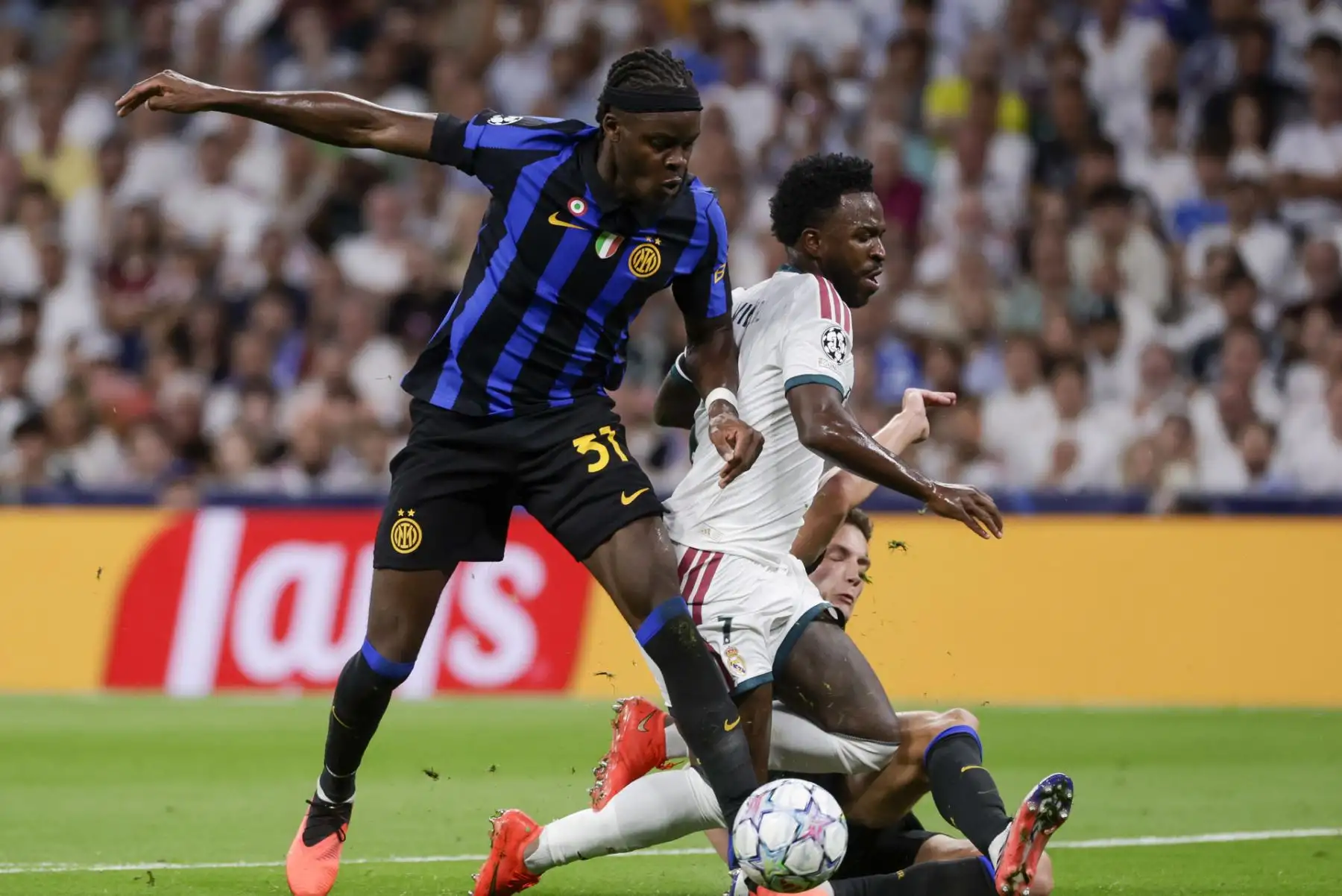El delantero del Real Madrid Vinicius Jr. (c) lucha con Yann Bisseck (i), del Inter, durante el encuentro correspondiente a la Liga de Campeones que disputan Real Madrid e Inter de Milán, este martes en el estadio Santiago Bernabéu, en Madrid. Foto: EFE