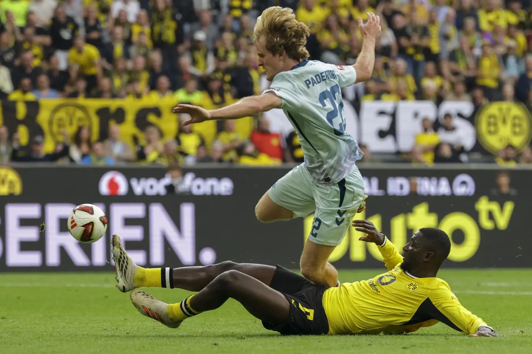 Mattes Hansen, del Paderborn (izq.), en acción contra Serhou Guirassy, ​​del Dortmund (der.), durante el partido de la Bundesliga alemana de fútbol entre el Borussia Dortmund y el SC Paderborn 07 en Dortmund, Alemania, el 12 de septiembre de 2026.
 Foto: EFE