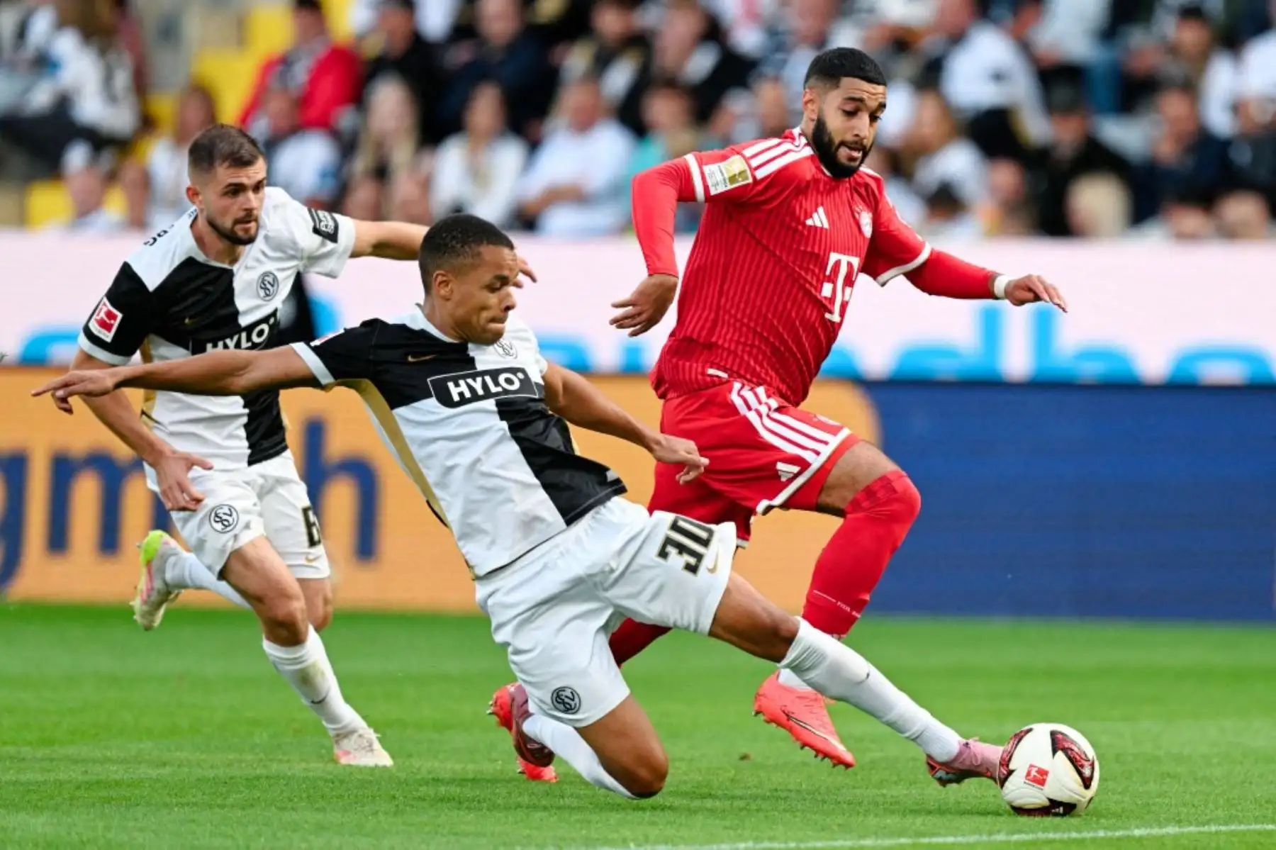 13 September 2026, Saarland, Spiesen-Elversberg: Soccer, Men: Bundesliga, SV Elversberg vs. Bayern Munich, Matchday 3, Ursapharm-Arena an der Kaiserlinde. Jan Gyamerah (C, SV 07 Elversberg) and Ismael Saibari (R, Bayern Munich) battle for the ball. Behind them runs Łukasz Poręba (SV 07 Elversberg).  Foto: AFP