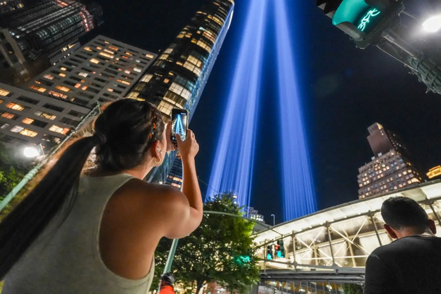 Una persona toma una fotografía de la instalación de arte público "Tributo en Luz", que conmemora los ataques terroristas del 11 de septiembre de 2001, mientras brilla en el horizonte del bajo Manhattan en preparación para el 25 aniversario, en la ciudad de Nueva York, el 10 de septiembre de 2026. (Foto de Ryan MURPHY / AFP)