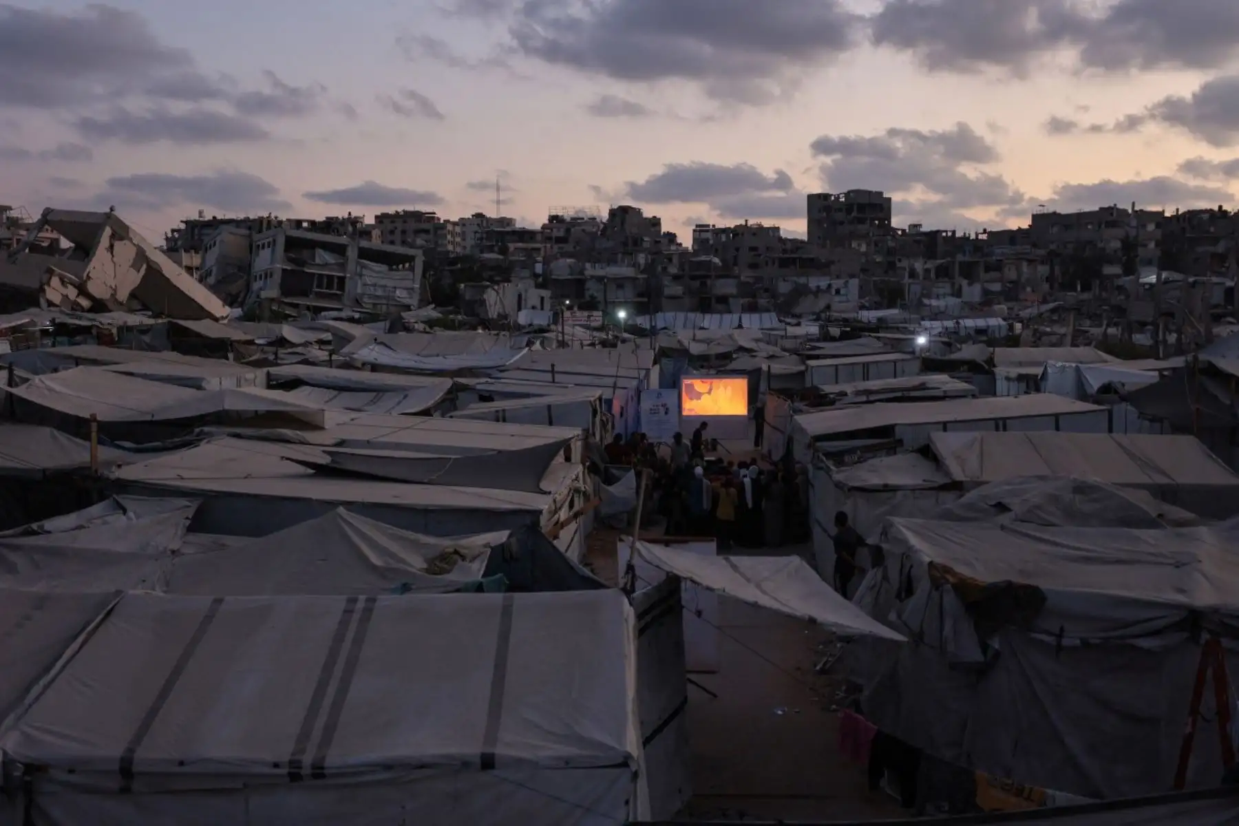 Niños palestinos se reúnen entre las tiendas de campaña para ver una proyección de dibujos animados al aire libre, como parte de la iniciativa móvil Little Wings Cinema, en un campamento para personas desplazadas por la guerra en la ciudad de Gaza, el 5 de septiembre de 2026. (Foto de Omar AL-QATTAA / AFP)