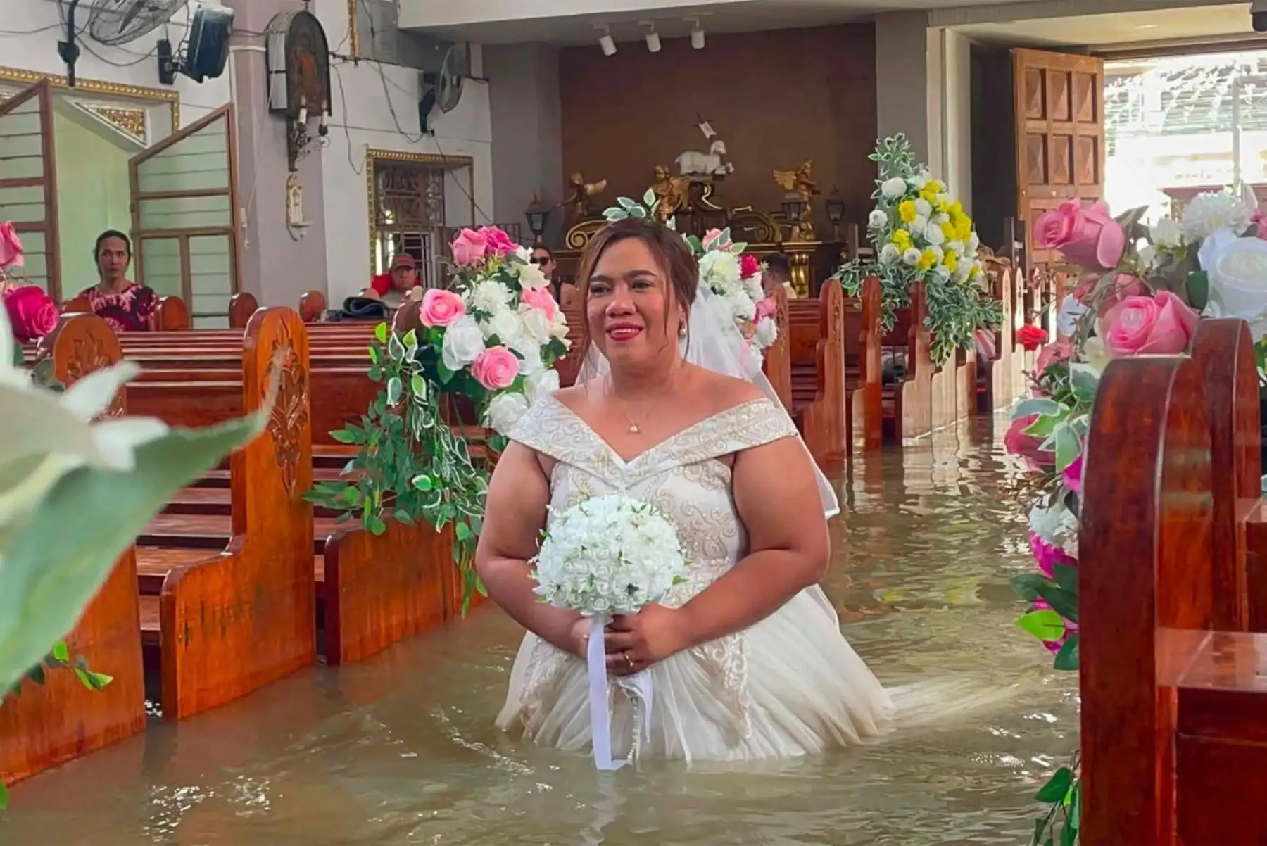 La novia Leian Lieza Galang camina hacia el altar durante su ceremonia nupcial en una iglesia inundada en el pueblo de Hagonoy. Una pareja filipina contrajo en una iglesia católica anegada con agua hasta la cintura, debido a las fuertes lluvias que han azotado gran parte del país durante un mes. Foto: AFP