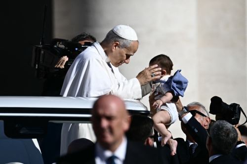 Papa León XIV bendice a un niño a su llegada a la audiencia general en el Vaticano