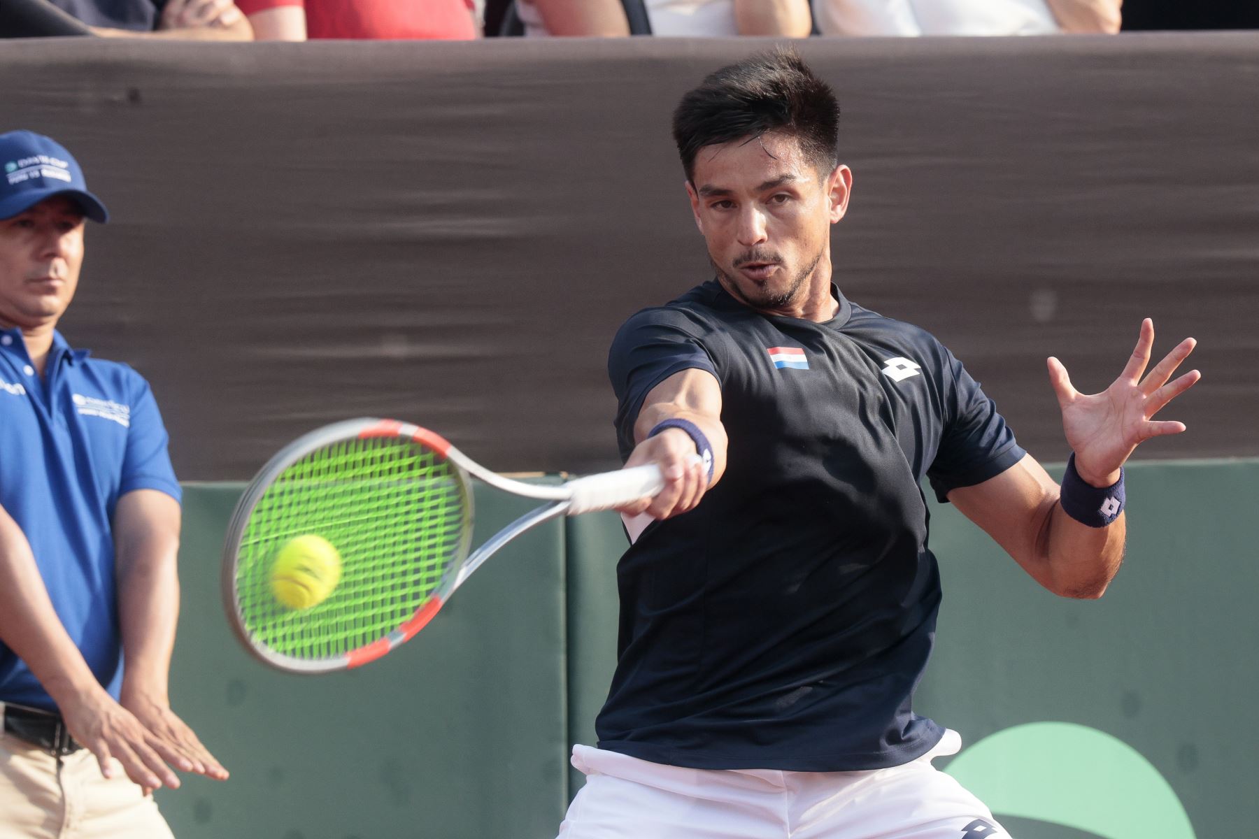Tras una intensa batalla de 3 horas y 9 minutos, el tenista peruano Ignacio Buse derrotó al paraguayo Hernando Escurra y le dio a Perú su primer punto en la serie de la Copa Davis, correspondiente al Grupo Mundial I. En un encuentro marcado por la paridad y la resistencia de ambos jugadores, Buse se impuso por 7-6(4), 4-6 y 7-5, luego de un disputado tercer set que definió el triunfo nacional. Foto: ANDINA/Vidal Tarqui