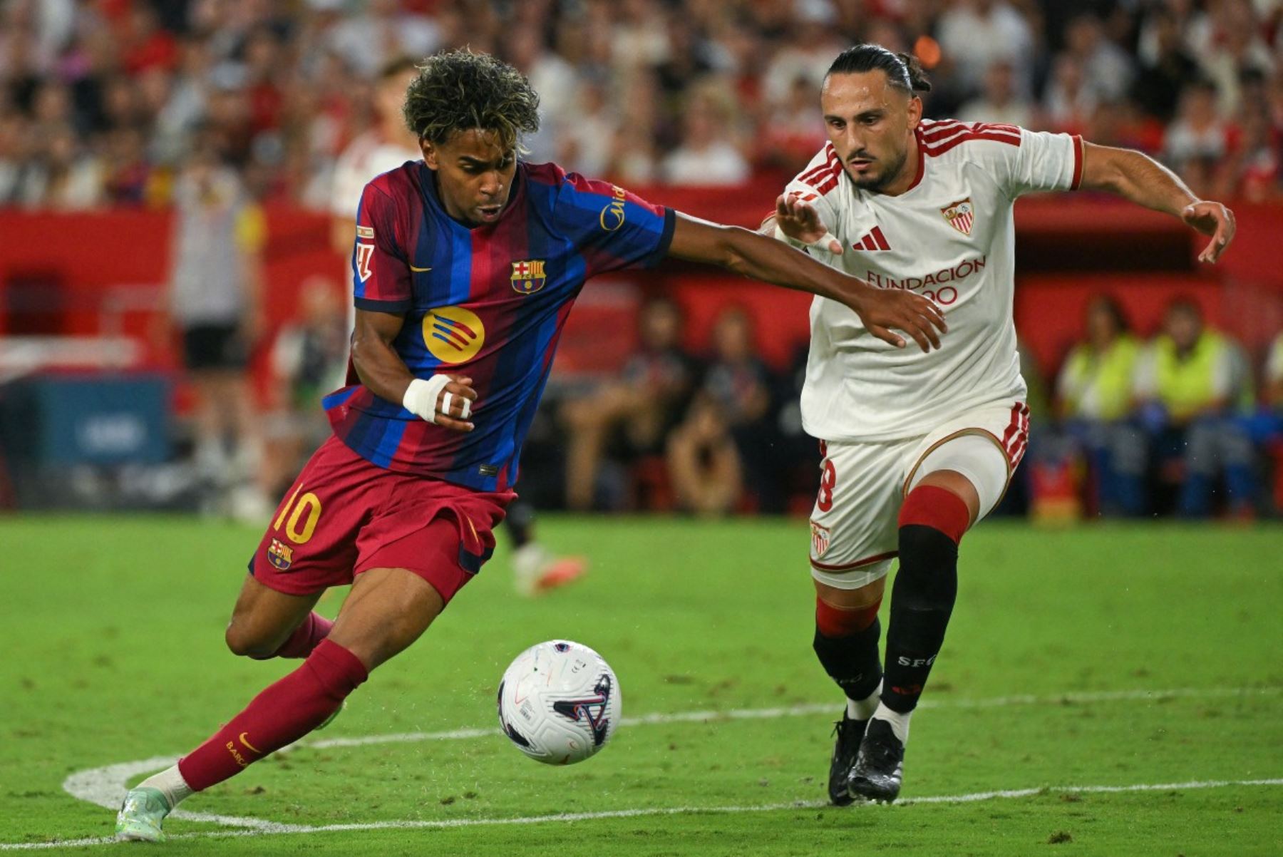 El delantero español del Barcelona, ​​Lamine Yamal (número 10), y el centrocampista georgiano del Sevilla, Giorgi Kochorashvili (número 8), luchan por el balón durante el partido de la liga española entre el Sevilla FC y el FC Barcelona en el estadio Ramón Sánchez Pizjuán de Sevilla, el 19 de septiembre de 2026. (Foto de JORGE GUERRERO / AFP)