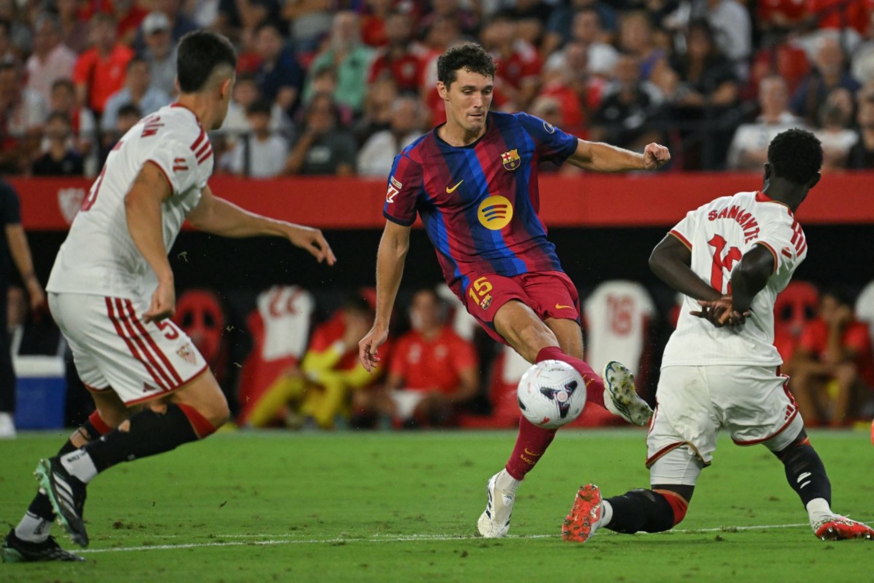 El defensa danés del Barcelona, ​​Andreas Christensen (número 15), patea el balón superando al defensa senegalés del Sevilla, Arouna Sangante (número 12), durante el partido de la liga española entre el Sevilla FC y el FC Barcelona en el estadio Ramón Sánchez Pizjuán de Sevilla, el 19 de septiembre de 2026. (Foto de JORGE GUERRERO / AFP)
