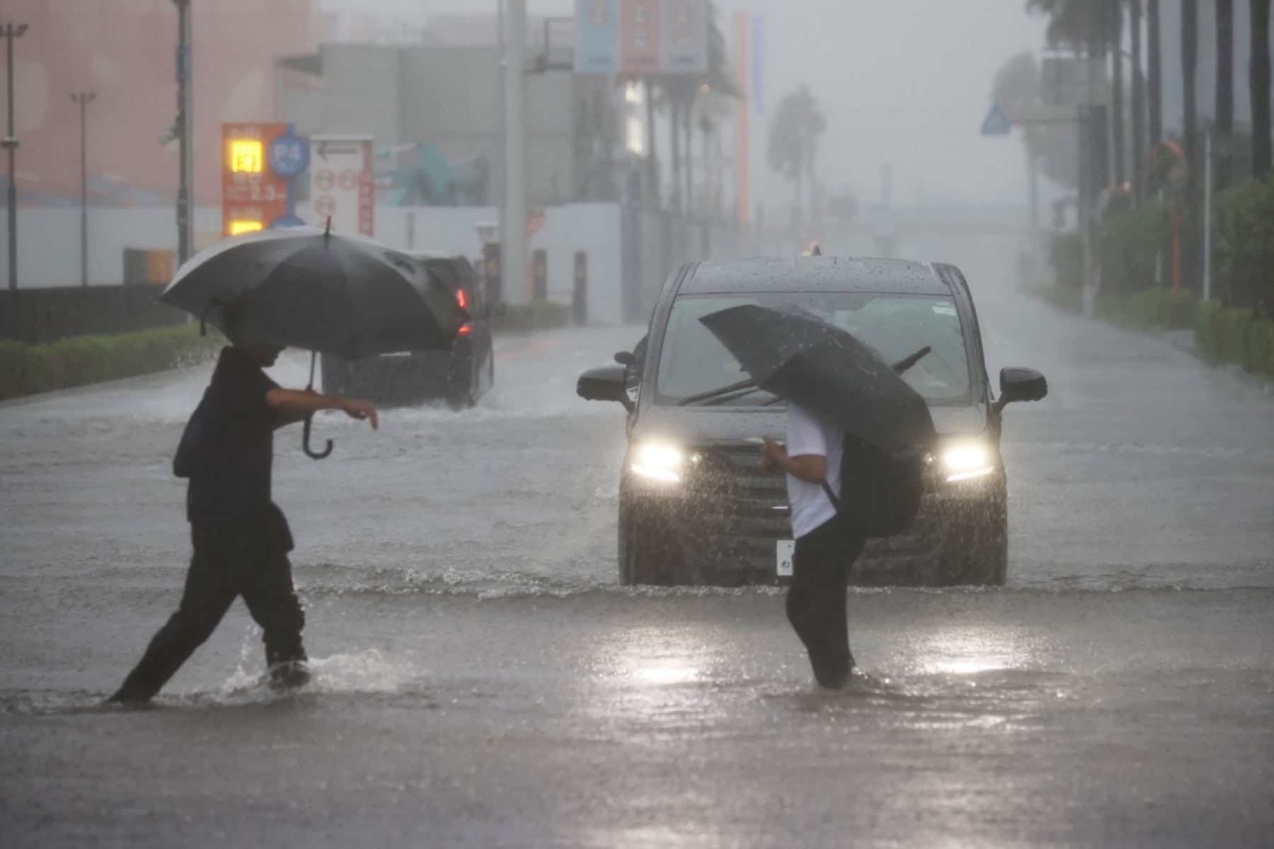 Varias personas caminan vadeando una carretera inundada mientras cae una lluvia torrencial debido a las condiciones meteorológicas provocadas por el tifón Dujuan en Funabashi, prefectura de Chiba, el 21 de septiembre de 2026. Foto: AFP