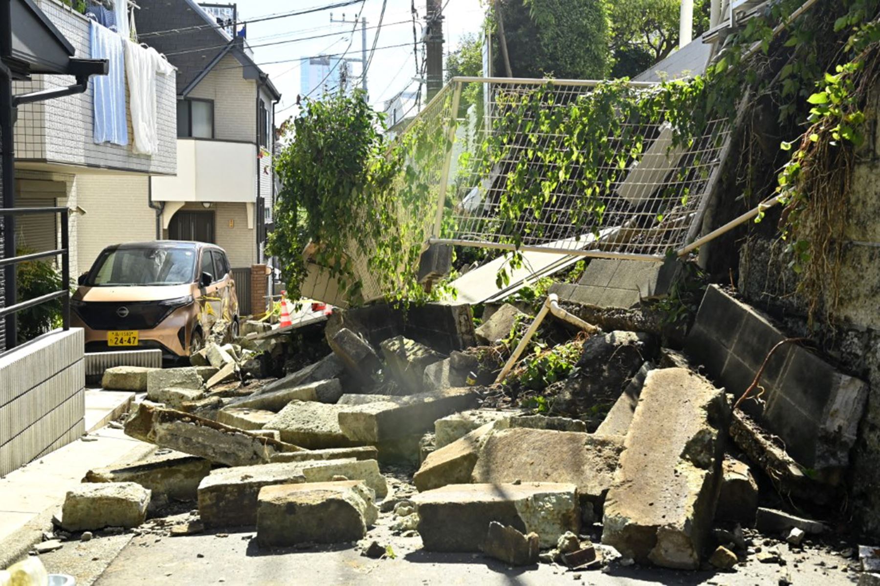 Escombros de un muro de contención residencial derrumbado bloquean una calle estrecha y rodean un vehículo dañado tras las fuertes lluvias provocadas por el tifón Dujuan en la zona de Naka-Meguro, Tokio (Japón). Foto: AFP
