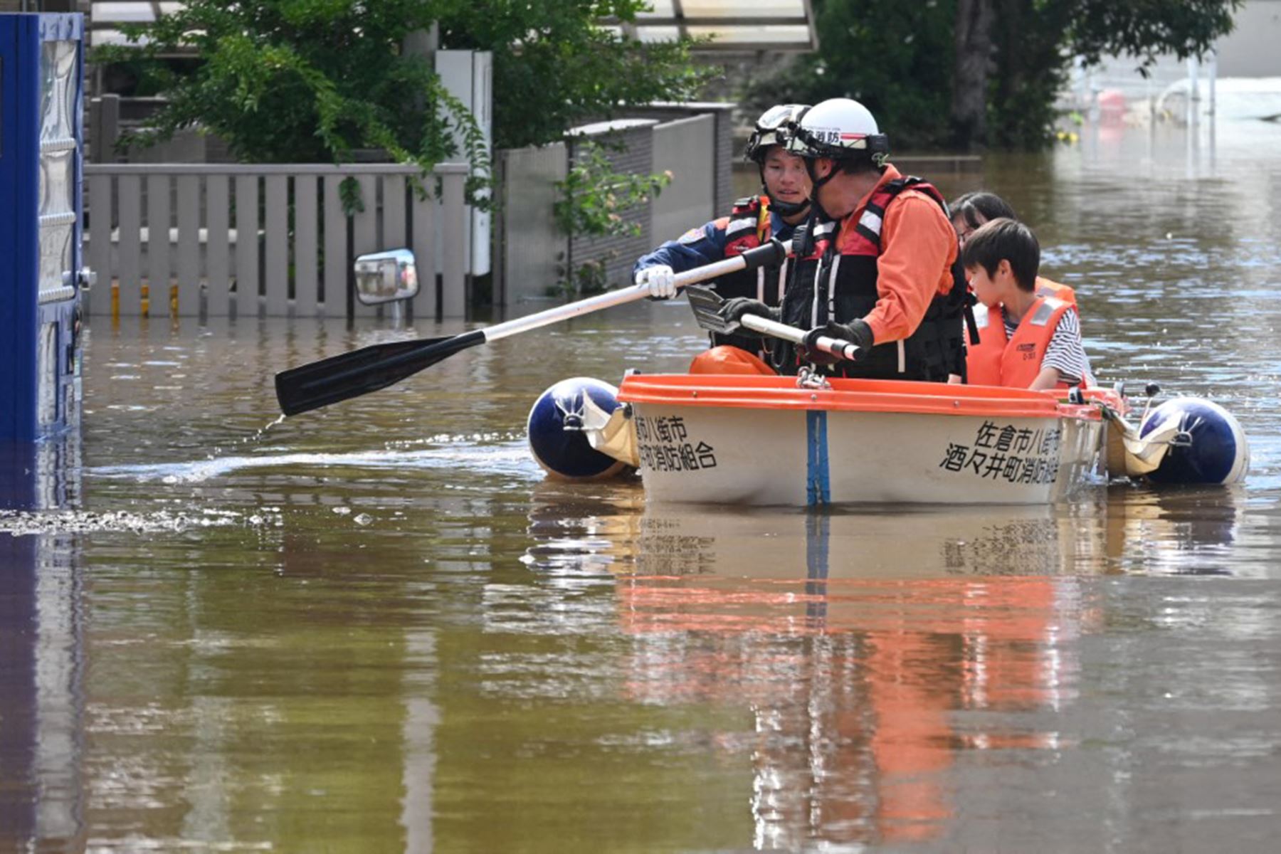 Bomberos navegan en un bote por una calle inundada para rescatar a un padre y a su hijo de un apartamento aislado, tras las fuertes lluvias provocadas el día anterior por el tifón Dujuan en la ciudad de Sakura, prefectura de Chiba (Japón). Foto: AFP