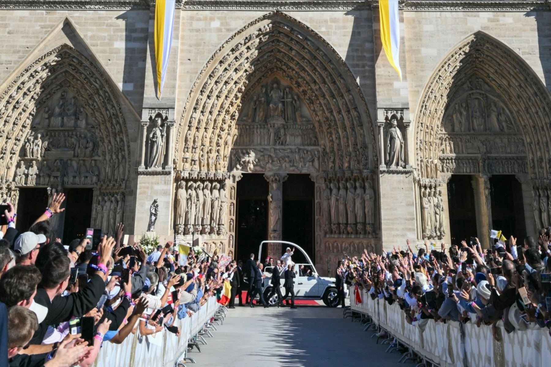 El papa León XIV, durante un recorrido por las calles de París, de pie en un papamóvil blanco descubierto y saludando a la multitud. Se observan miembros del clero, personal de seguridad, banderas y espectadores a lo largo de la calle parisina durante el recorrido papal. Foto: AFP