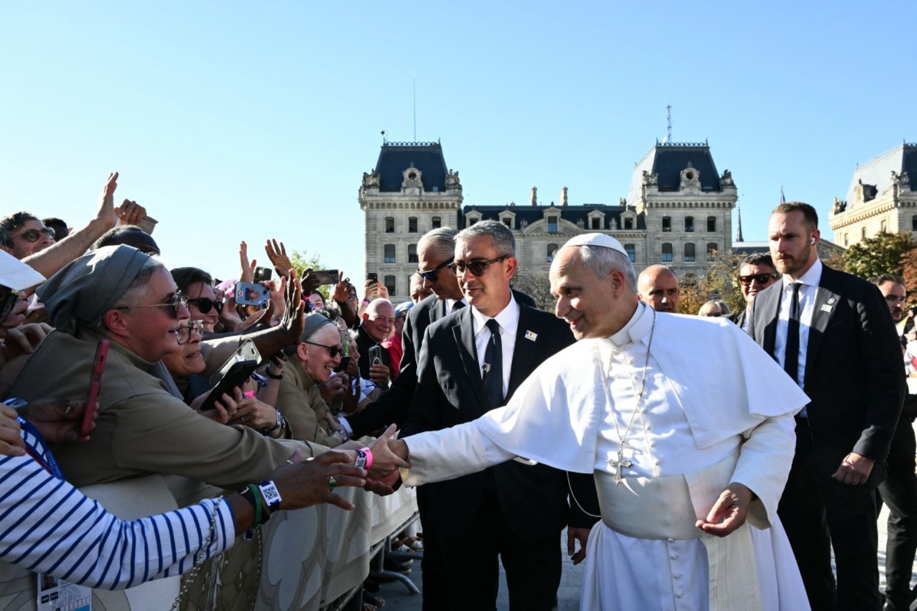 El papa León XIV, durante un recorrido por las calles de París, saludando a la multitud. Se observan miembros del clero, personal de seguridad, banderas y espectadores a lo largo de la calle parisina durante el recorrido papal. Foto: AFP