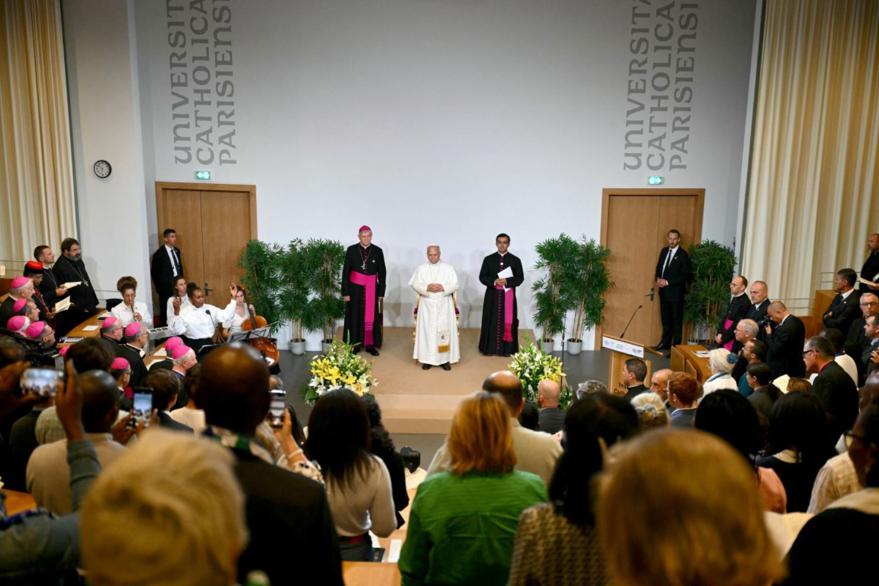 El Papa León XIV y el arzobispo francés Laurent Ulrich (izquierda) y el secretario privado del Papa, Edgard Ivan Rimaycuna Inga, permanecen en el escenario al inicio de un encuentro con miembros de la Asamblea Sinodal Provincial de Francia, catecúmenos y neófitos en el Instituto Católico de París. Foto: ANDINA/AFP