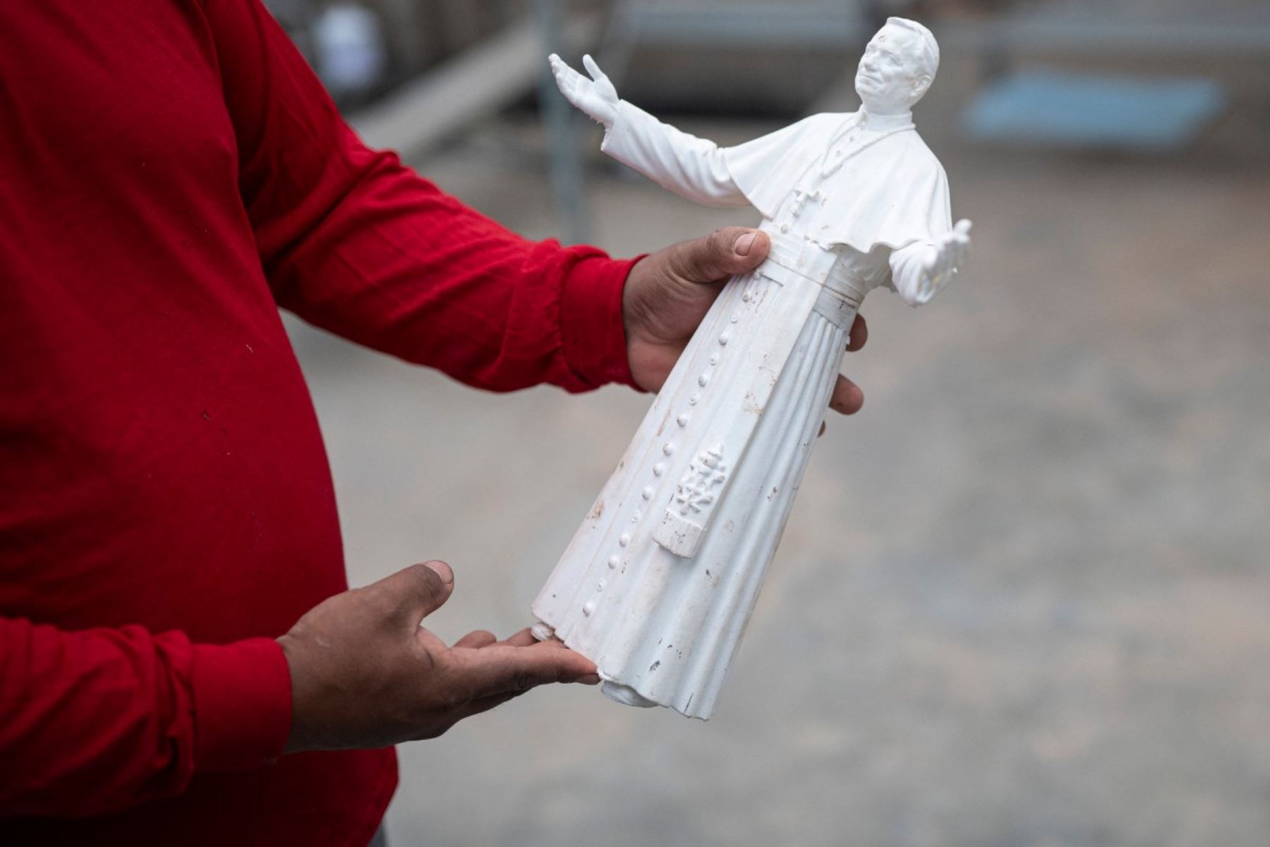 Rafael Gutiérrez, de 42 años, escultor egresado de la Escuela de Bellas Artes del Perú, sostiene un modelo de la escultura del papa León XIV durante su elaboración en su taller en el distrito de Carabayllo, en las afueras del norte de Lima. Foto: AFP
