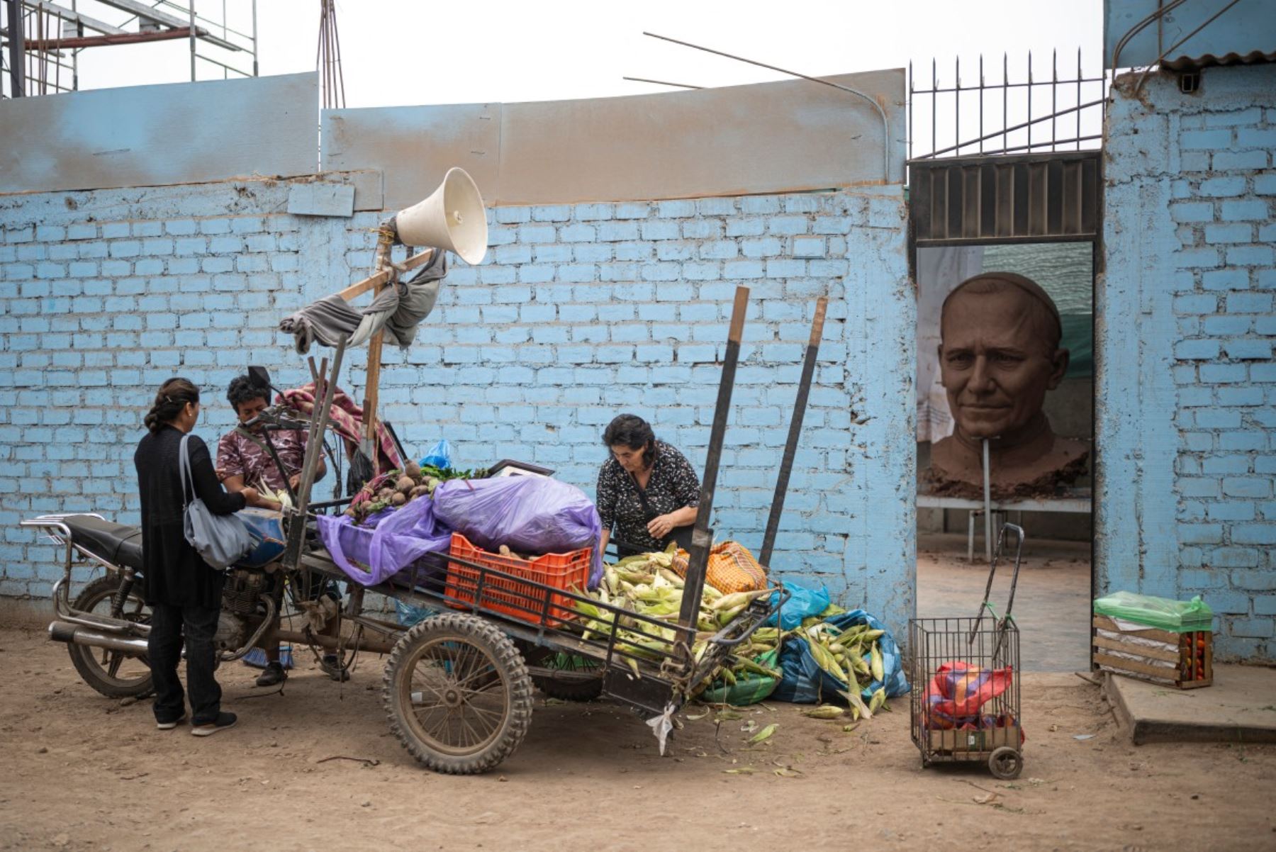 Un vendedor ambulante vende verduras frente al taller donde se está creando una escultura del papa León XIV, en el distrito de Carabayllo, en las afueras norte de Lima. Foto: AFP