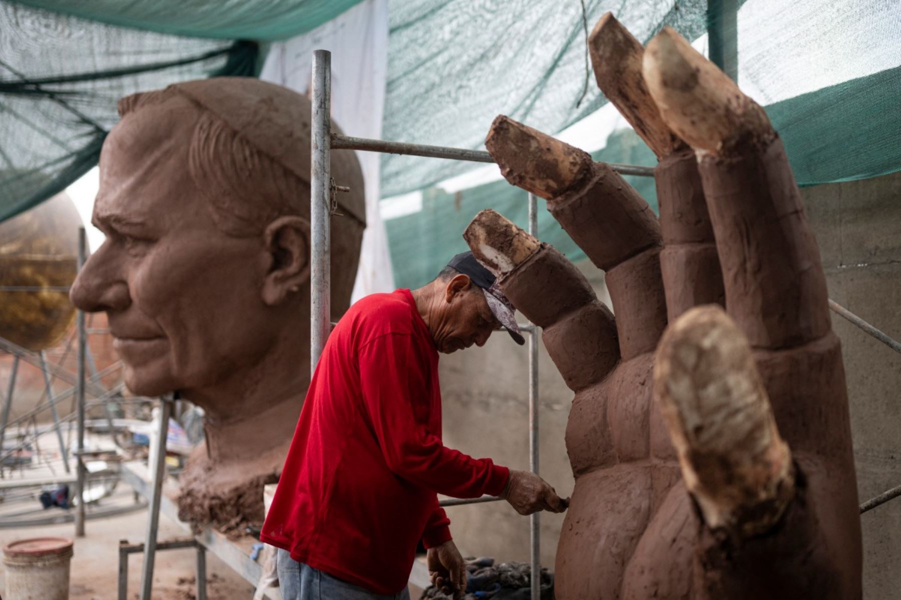Un artesano trabaja en la mano de una escultura del papa León XIV durante su elaboración en un taller en el distrito de Carabayllo, en las afueras norte de Lima. Foto: AFP