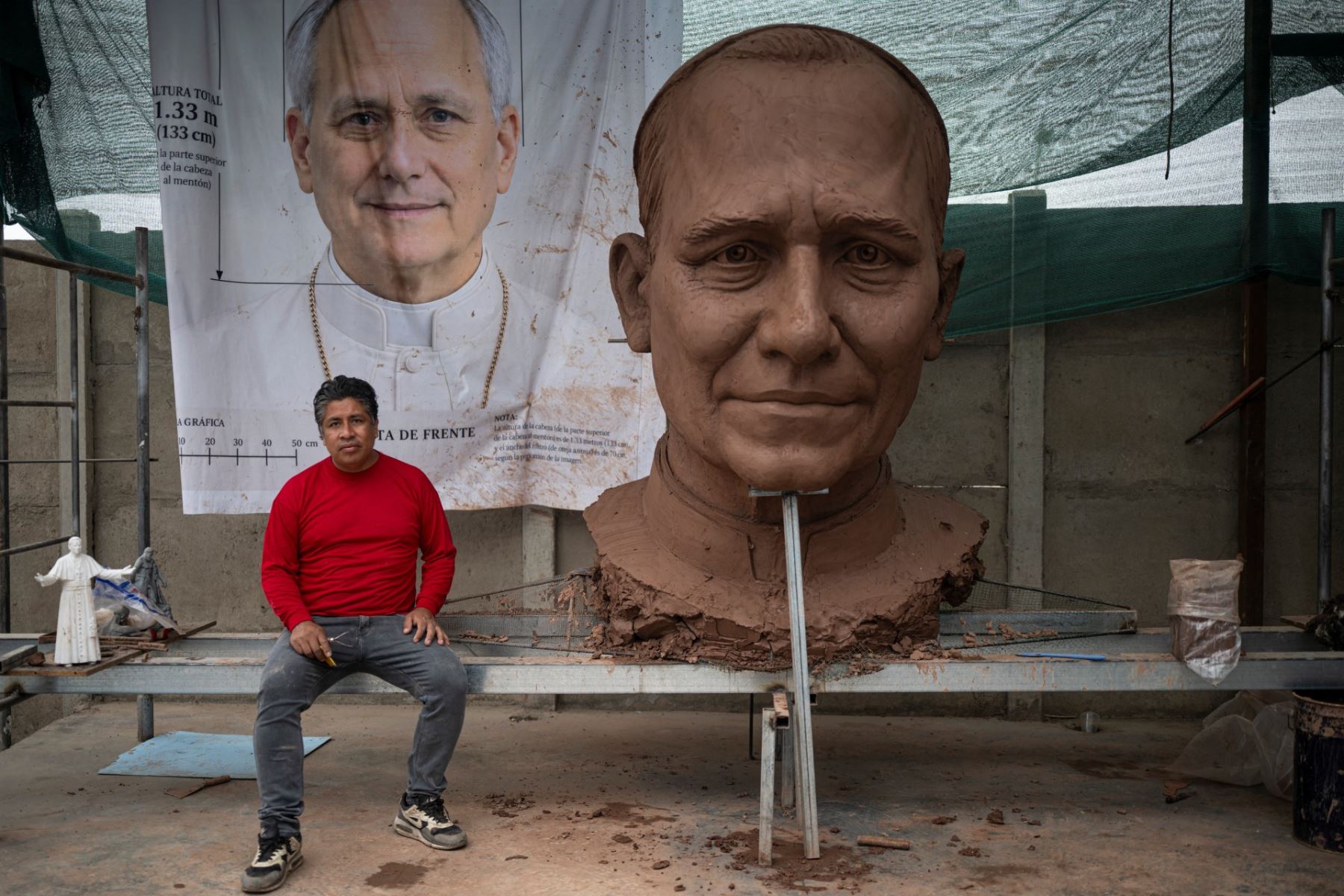 Rafael Gutiérrez, de 42 años, escultor egresado de la Escuela de Bellas Artes del Perú, posa para una foto junto a la cabeza de una escultura del papa León XIV durante su elaboración en su taller en el distrito de Carabayllo, en las afueras del norte de Lima. Foto: AFP