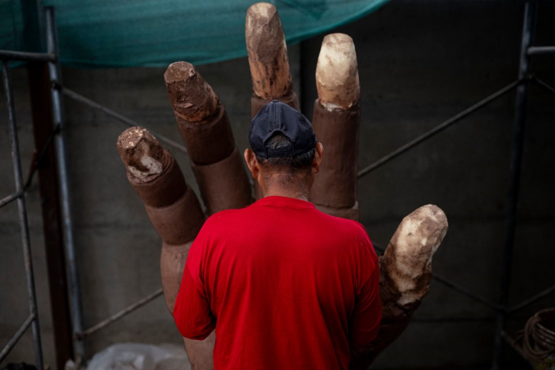 Un artesano trabaja en la mano de una escultura del papa León XIV durante su elaboración en un taller en el distrito de Carabayllo, en las afueras norte de Lima. Foto: AFP