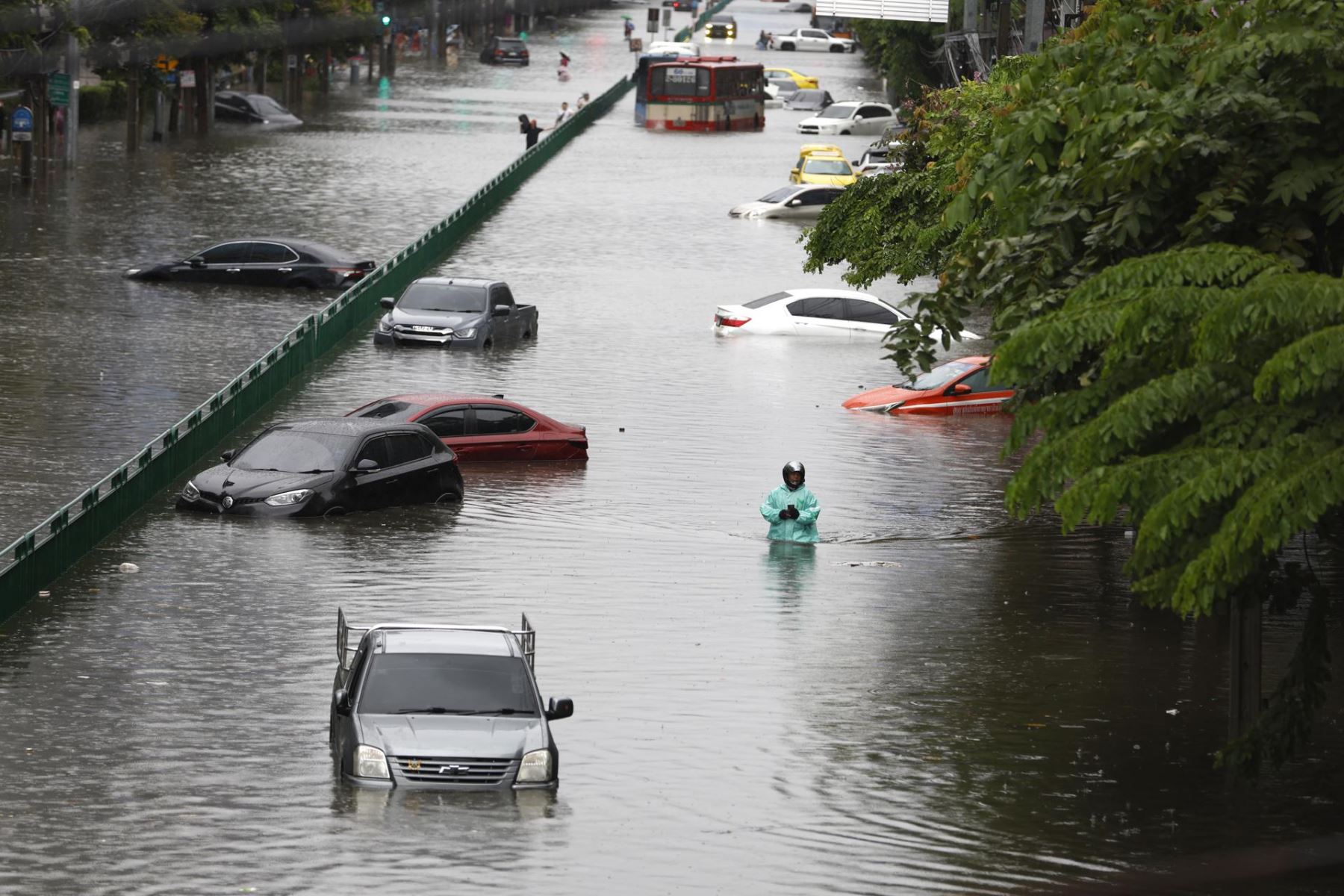 Un automovilista avanza a pie por el agua mientras vehículos sumergidos quedan abandonados durante un fuerte aguacero en una vía principal anegada —la calle Phetchaburi— en Bangkok, Tailandia Foto: EFE