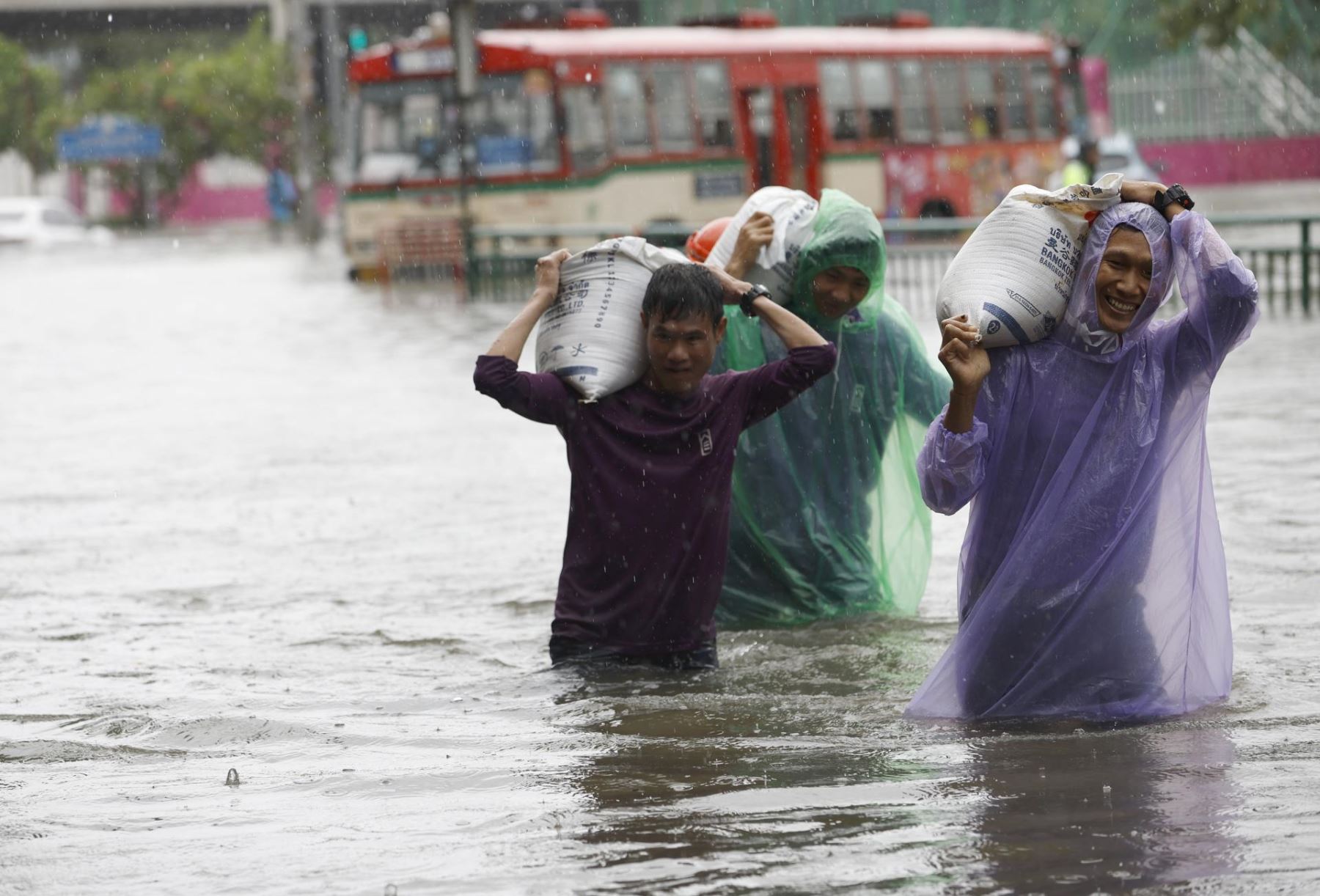 Unos trabajadores transportan sacos de arena bajo un fuerte aguacero en una calle principal inundada, la carretera Phetchaburi de Bangkok (Tailandia) Foto: EFE