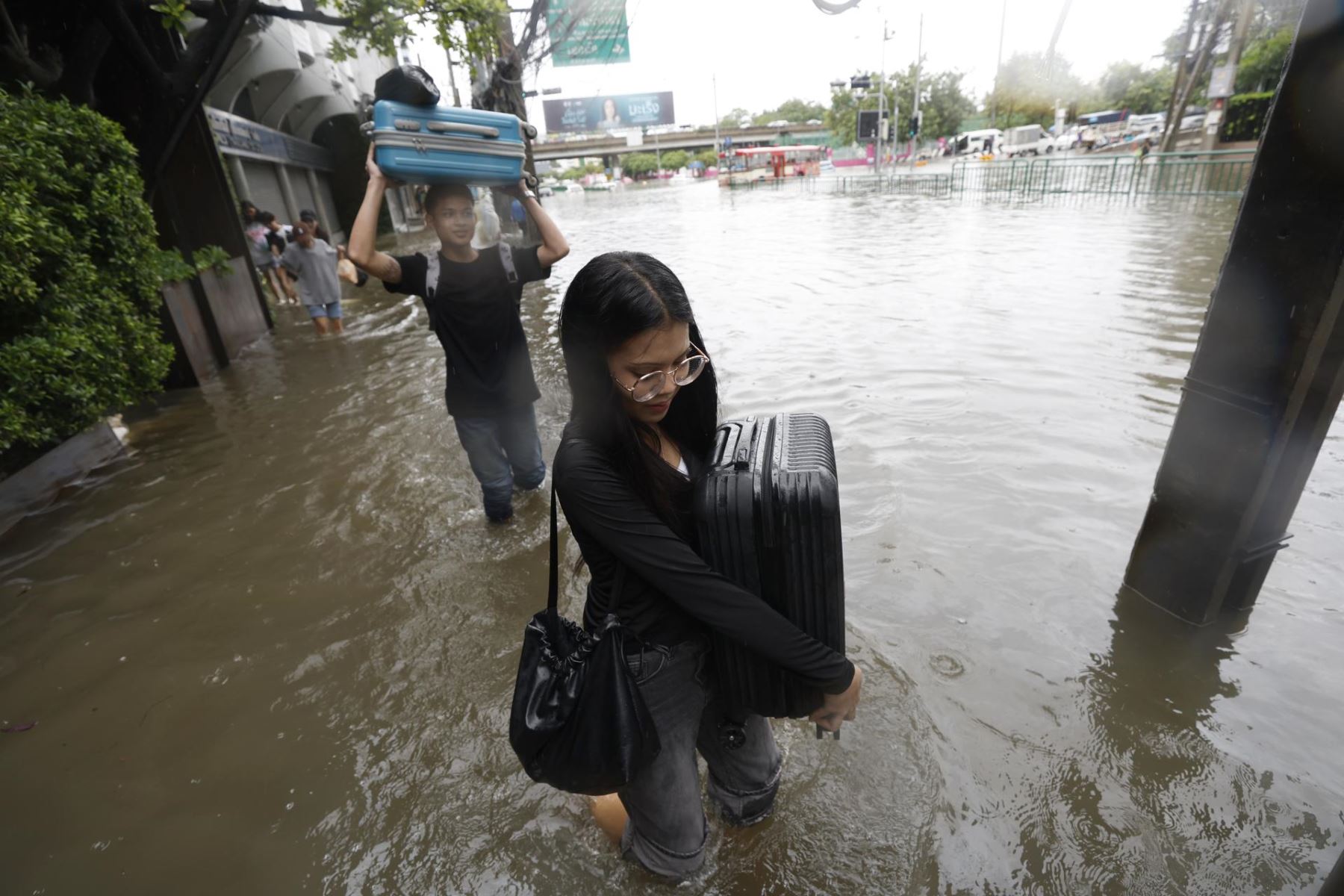 Personas que transportan sus pertenencias caminan por aguas de inundación durante un fuerte aguacero en Bangkok Foto: EFE