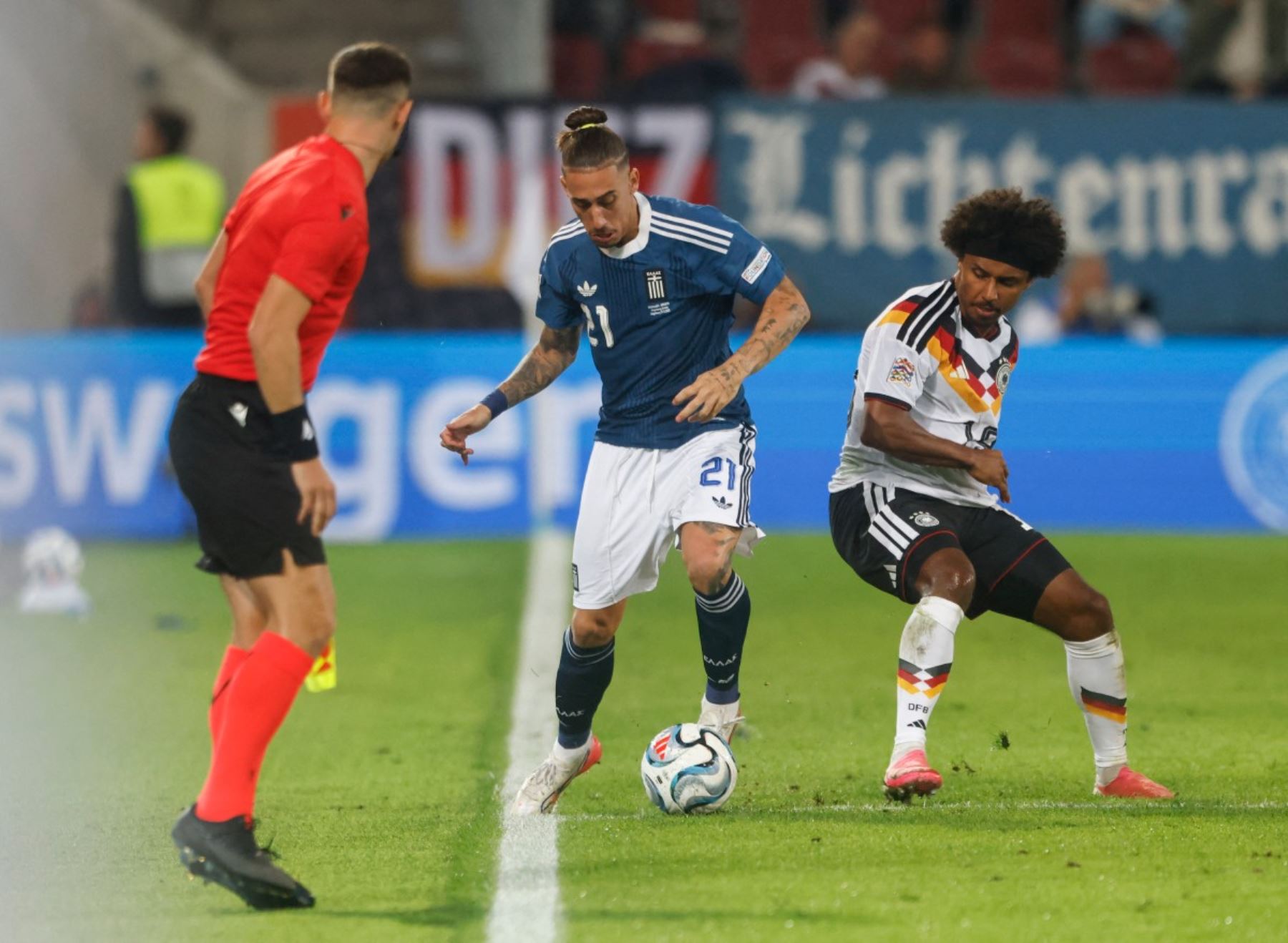 El defensa griego Konstantinos Tsimikas (número 21) y el centrocampista alemán Karim Adeyemi (número 19) disputan el balón durante el partido de la fase de grupos A2 de la Liga de Naciones de la UEFA entre Alemania y Grecia en Augsburgo, al sur de Alemania, el 27 de septiembre de 2026. (Foto de Michaela STACHE / AFP)
