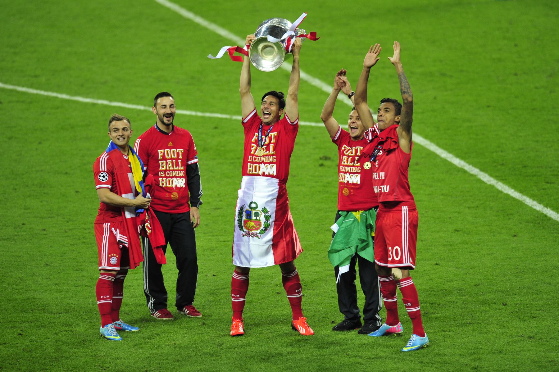 El delantero peruano del Bayern Munich, Claudio Pizarro, celebra con el trofeo en el campo junto a sus compañeros de equipo después de su victoria en la final de la UEFA Champions League entre el Borussia Dortmund y el Bayern Munich, en el estadio de Wembley en Londres, el 25 de mayo de 2013. Foto: AFP