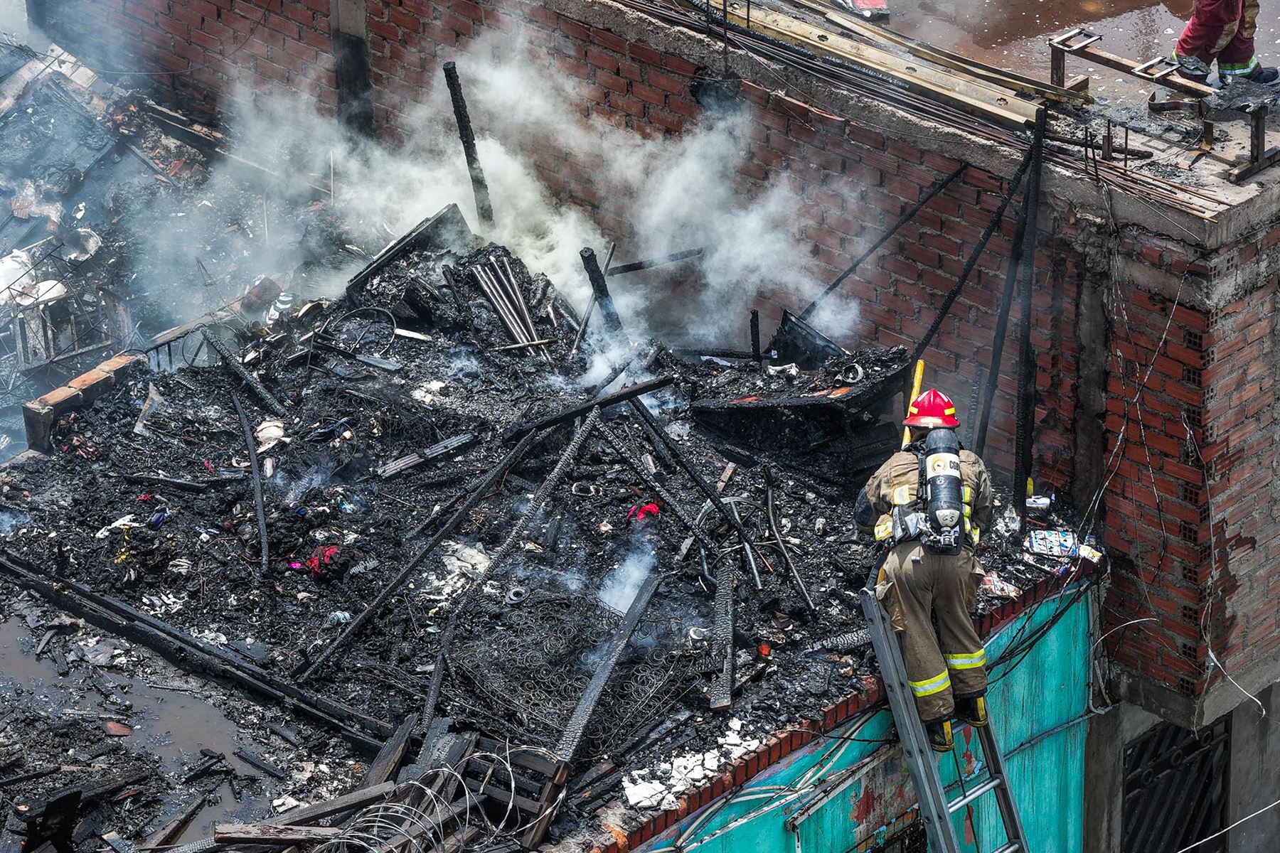 Bomberos trabajan en la zona donde se registró un incendio en el cruce de los jirones Madera y Trujillo, en el distrito del Rímac. La emergencia ya fue controlada. Foto: ANDINA/Daniel Bracamonte
