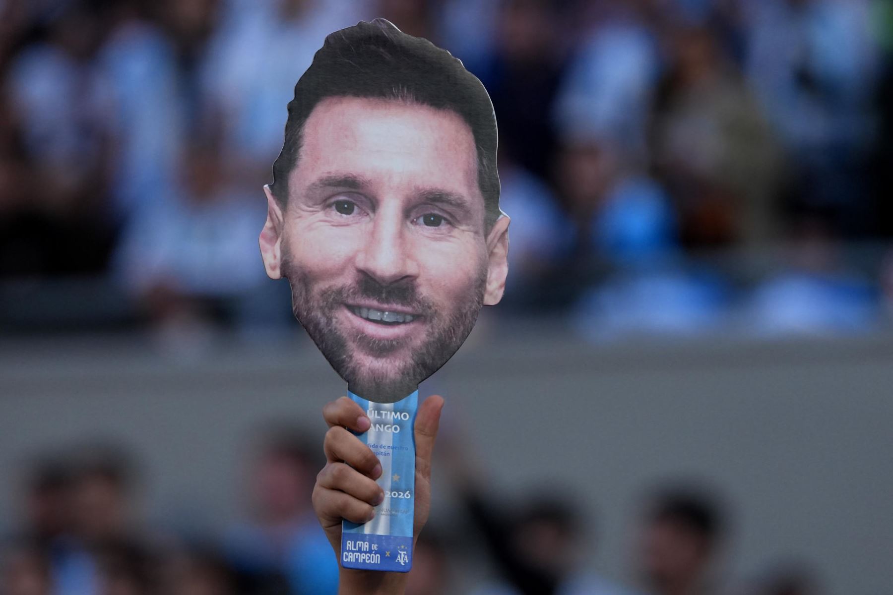 Una persona sostiene una mascara con la imagen de Lionel Messi este martes, previo a un partido amistoso internacional entre Argentina y Benín en el estadio Monumental, en Buenos Aires (Argentina). Parece la previa de una final de Mundial: bombos, banderas gigantes y miles de camisetas con el 10 en la espalda. Pero la marea albiceleste que llega al Monumental lo hace con una profunda tristeza, para presenciar un partido que nunca quiso ver: la despedida de Lionel Messi.  Foto: EFE