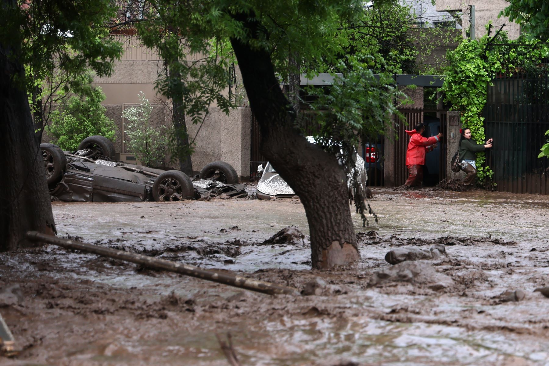 Personas caminan por una zona afectada por un aluvión este jueves, en la comuna de Las Condes, en Santiago de Chile. Foto: EFE