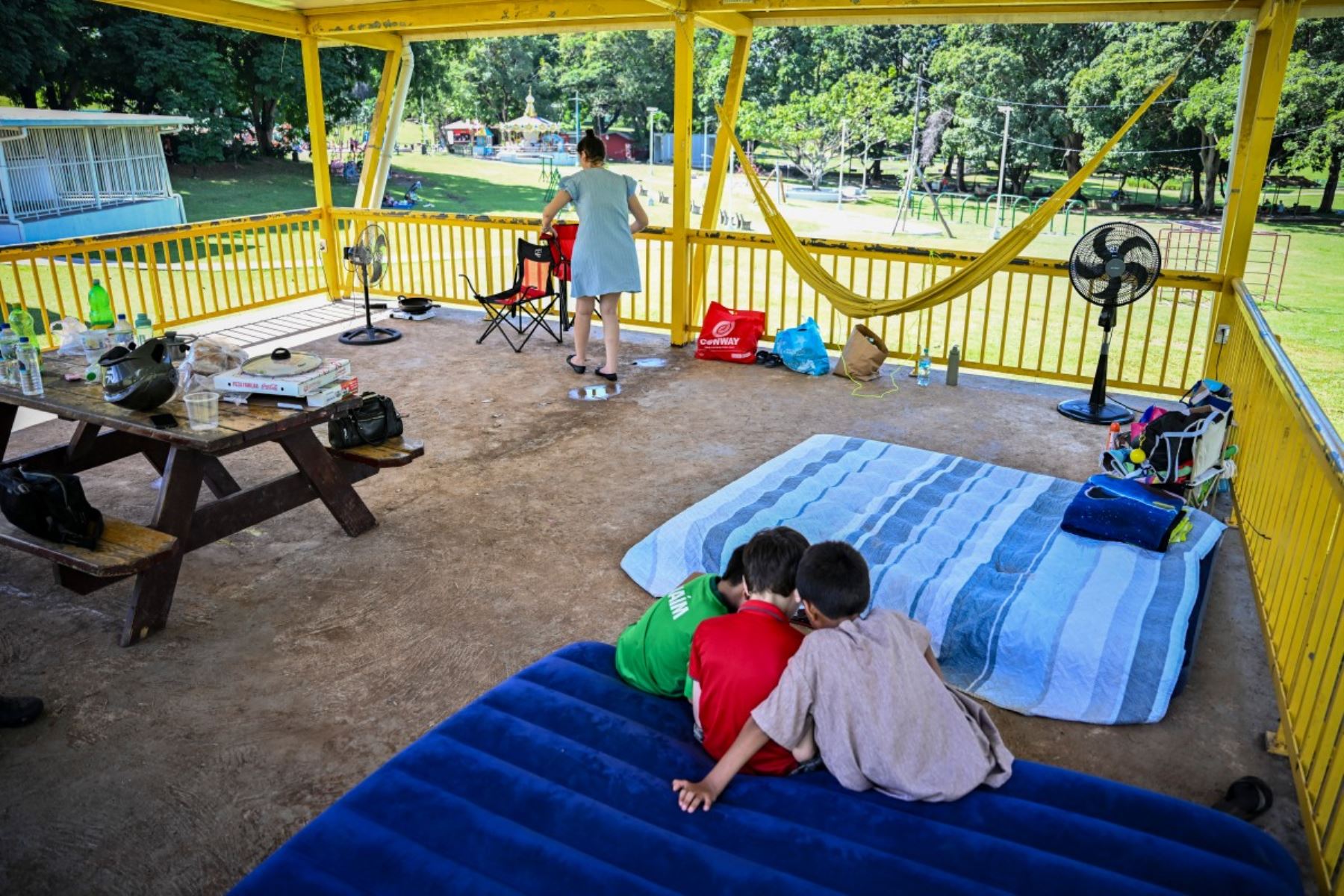 Una familia permanece en un pabellón del Parque Omar, en Ciudad de Panamá, el 10 de octubre de 2026, después de pasar la noche allí tras el terremoto que sacudió el país el día anterior.
Un potente terremoto de magnitud 7,7 sacudió Panamá el 10 de octubre de 2026, derrumbando edificios y carreteras en el centro del país y dejando al menos 27 personas heridas, sin que se hayan reportado fallecidos. Foto: AFP