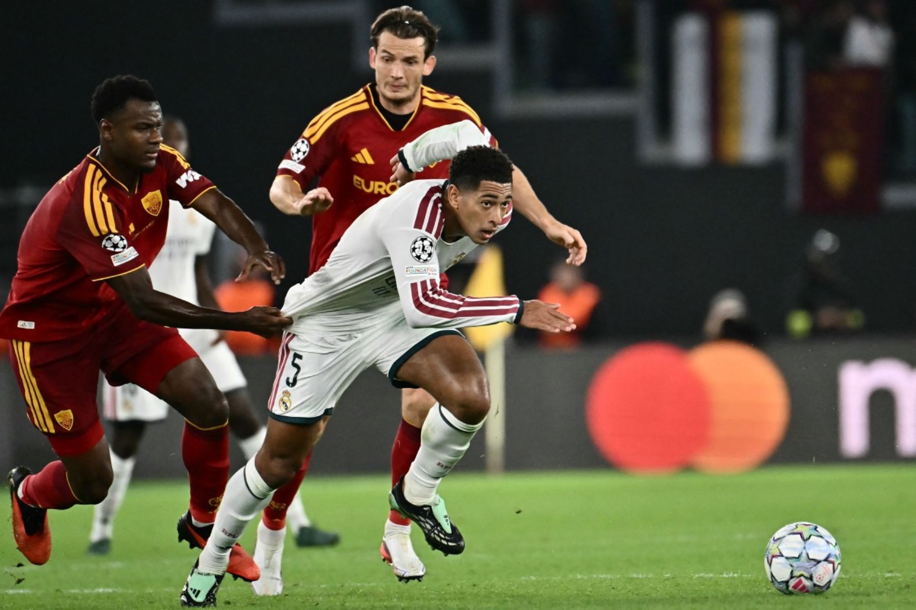 El centrocampista inglés del Real Madrid, Jude Bellingham (n.º 5), intenta zafarse del defensa marfileño de la AS Roma, Evan N