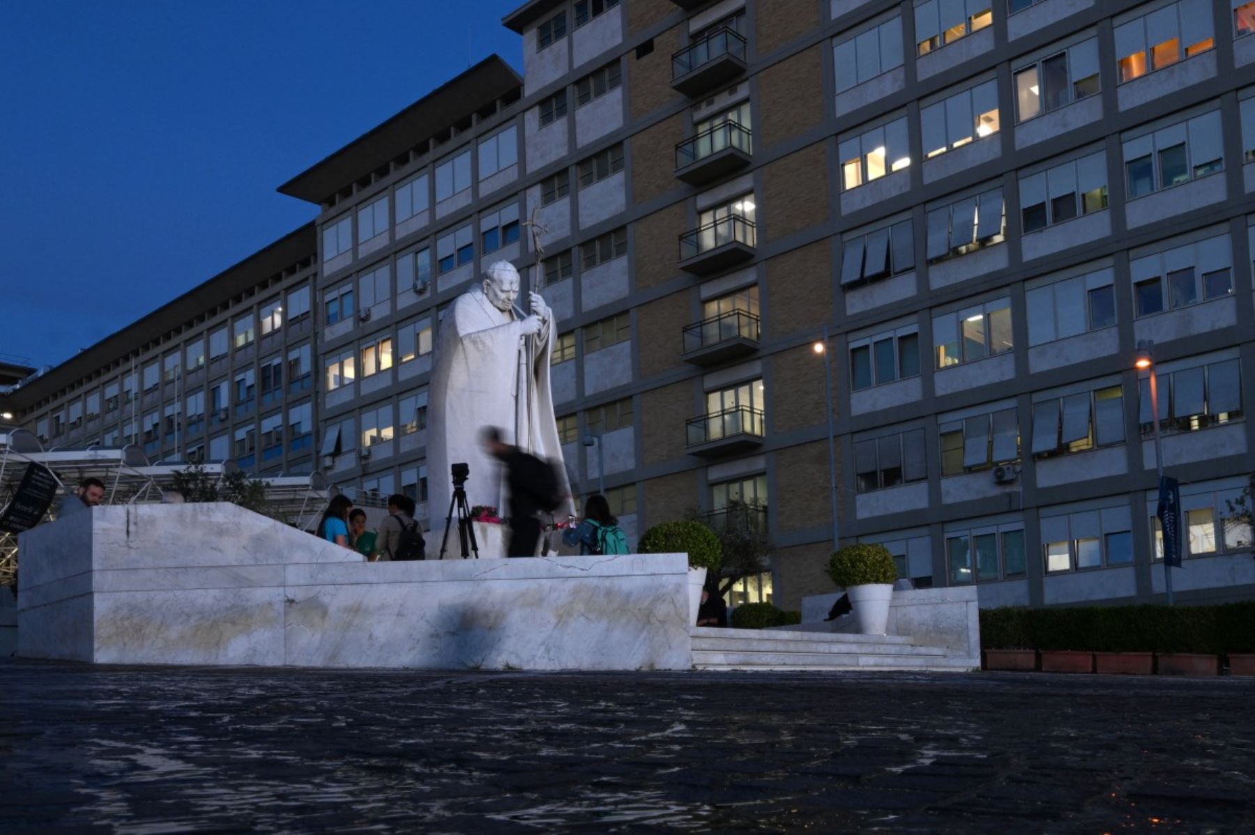 Personas rezan ante la estatua de Juan Pablo II en el exterior del Hospital Universitario Gemelli, donde el papa León XIV se recupera tras someterse a una intervención quirúrgica. Foto: AFP