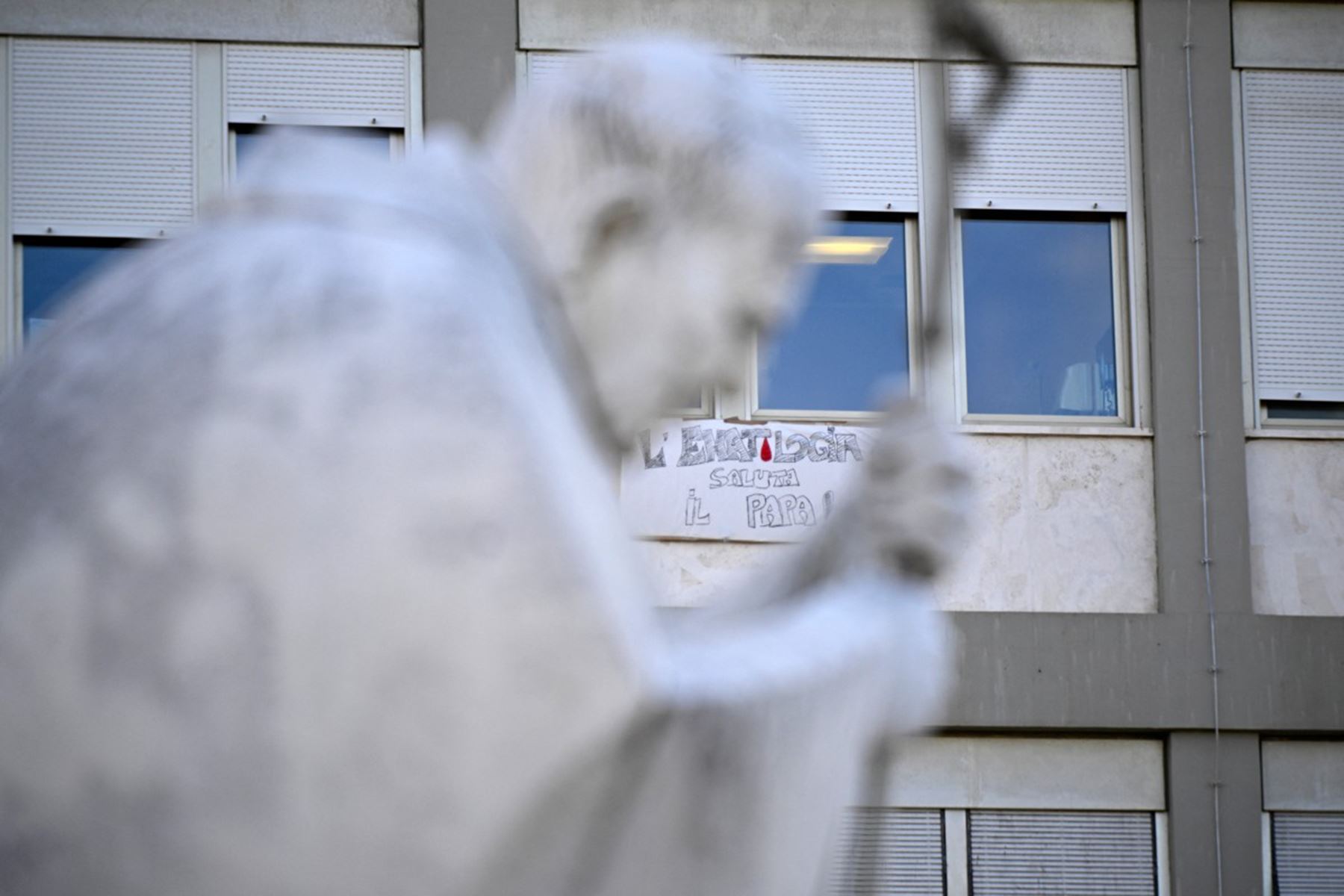 Estatua de Juan Pablo II en el exterior del Hospital Universitario Gemelli, donde el papa León XIV se recupera tras someterse a una intervención quirúrgica. Foto: AFP