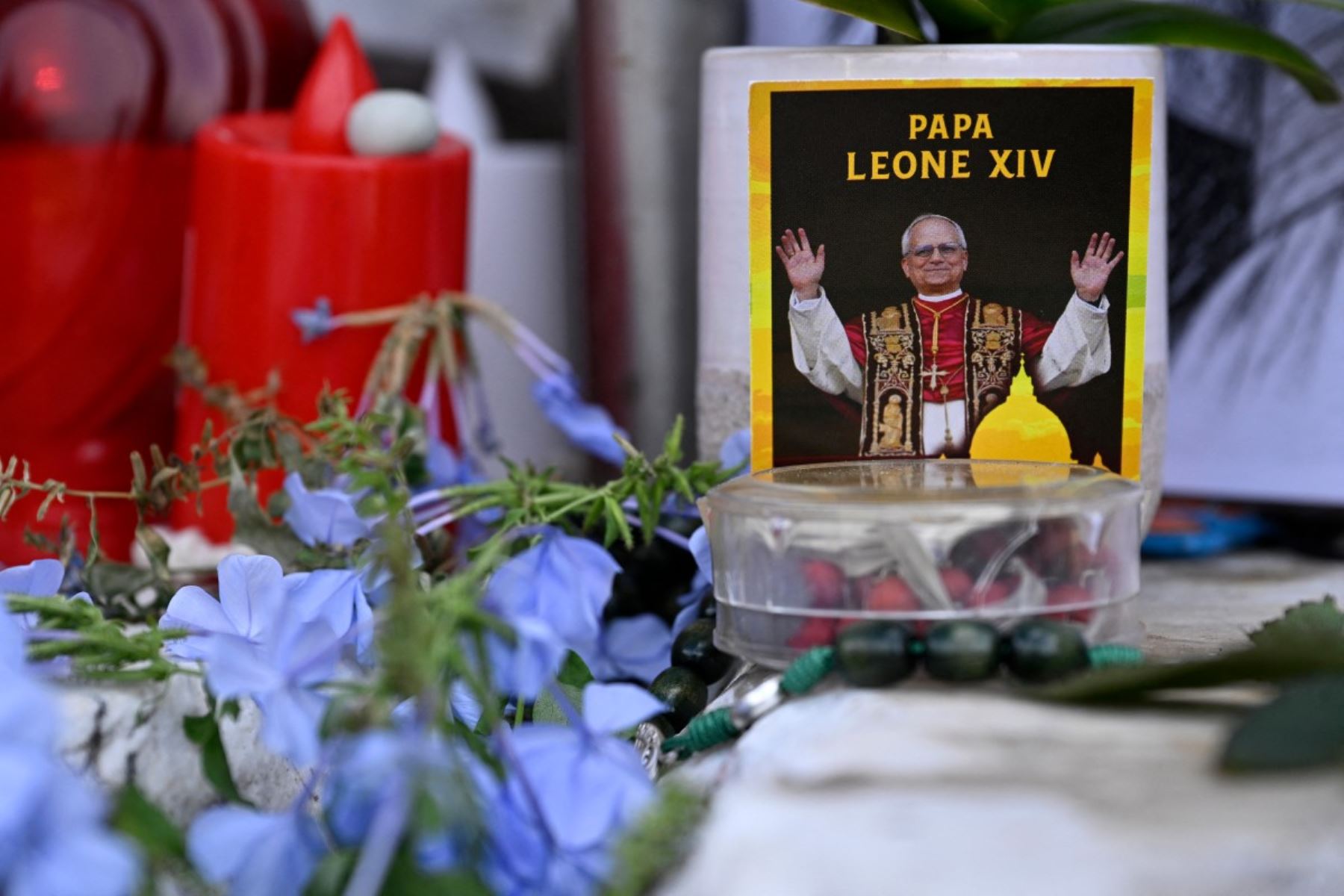 Flores, velas y una fotografía del Papa León XIV han sido depositadas junto a la estatua de Juan Pablo II, en el exterior del Hospital Universitario Gemelli, en Roma, donde el Papa León XIV se recupera tras someterse a una intervención quirúrgica para extirpar un tumor canceroso de su pulmón derecho. AFP