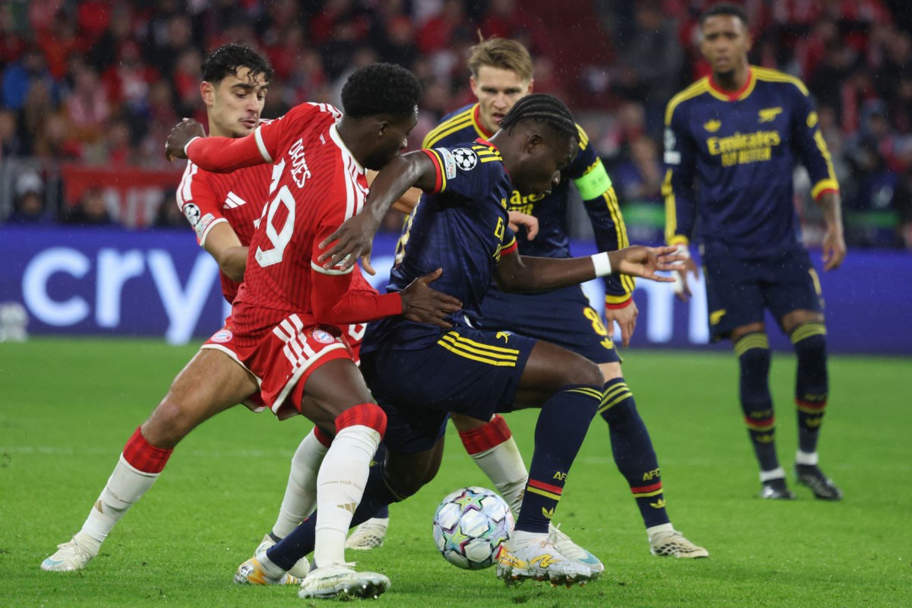 El centrocampista inglés del Arsenal, Bukayo Saka, y el defensa canadiense del Bayern de Múnich, Alphonso Davies, disputan el balón durante el partido de la Liga de Campeones de la UEFA entre el FC Bayern de Múnich y el Arsenal FC, celebrado en Múnich, en el sur de Alemania. Foto: ANDINA/AFP