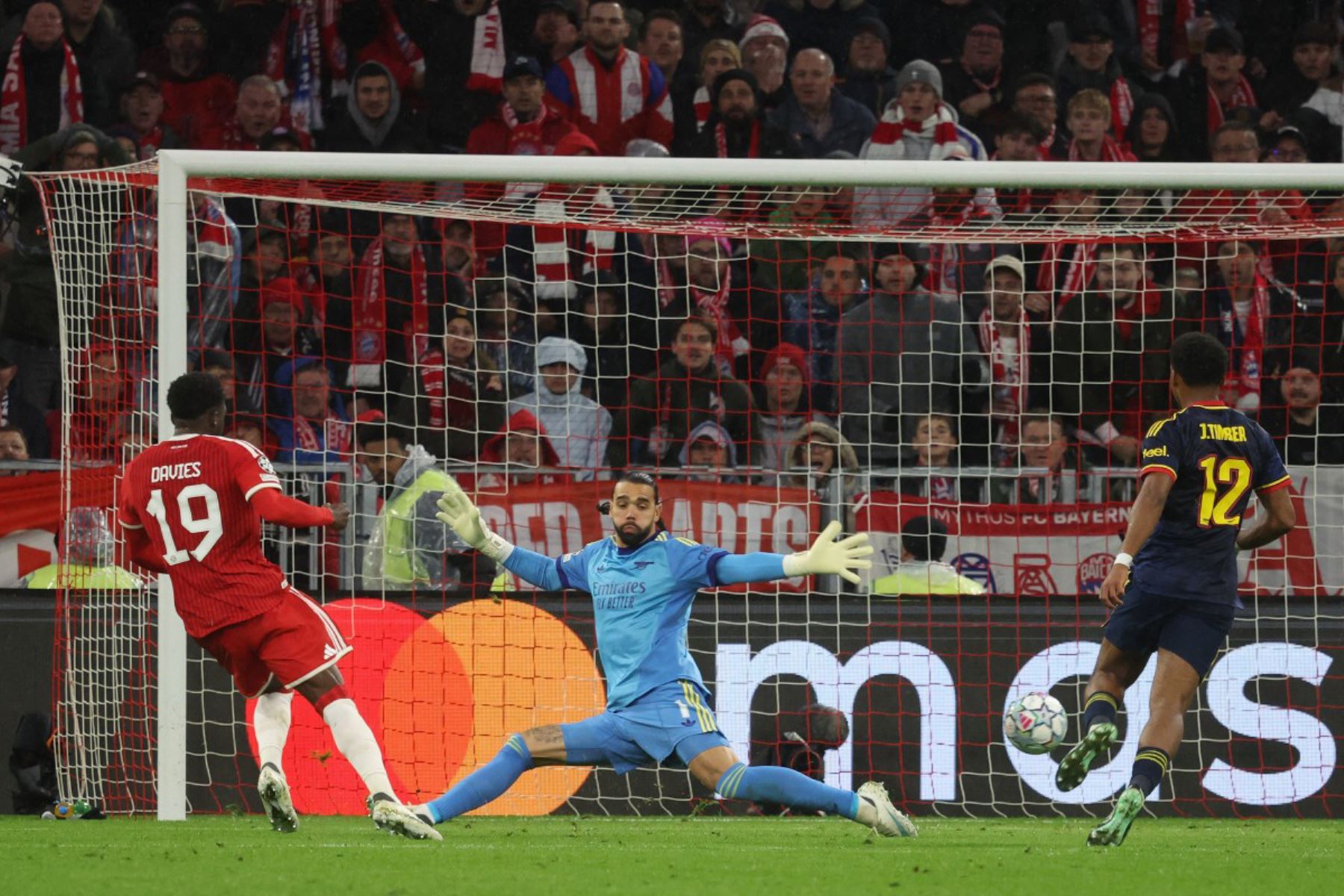 El defensa canadiense del Bayern de Múnich, Alphonso Davies, anota el gol del 1-1 ante el portero español del Arsenal, David Raya, durante el partido de la Liga de Campeones de la UEFA entre el FC Bayern de Múnich y el Arsenal FC, disputado en Múnich, en el sur de Alemania.
Foto: ANDINA/AFP