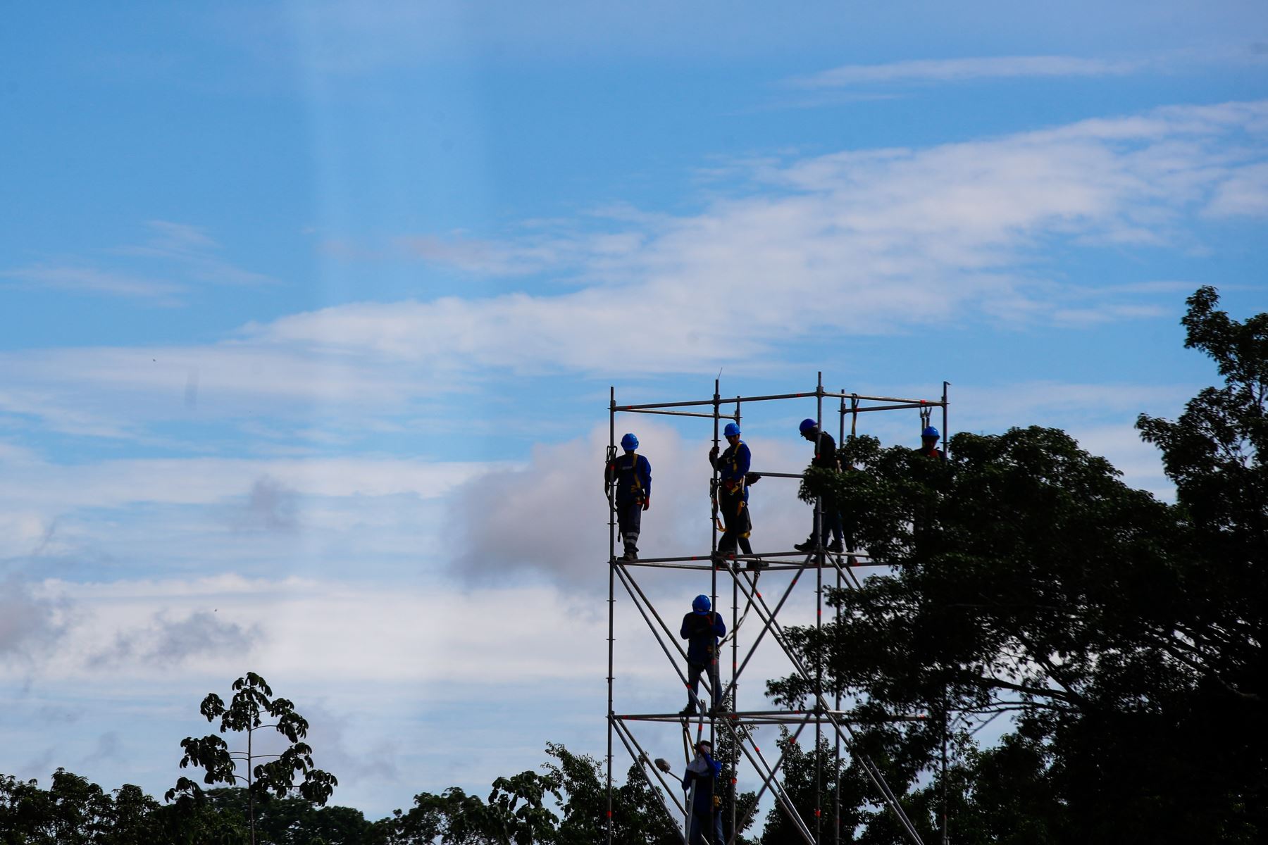 Obreros realizan trabajos en altura durante el montaje de las estructuras metálicas que sostendrán el escenario principal en el complejo deportivo La Videnita, en Pucallpa, donde se celebrará la misa del papa León XIV. Foto: ANDINA/Ricardo Cuba