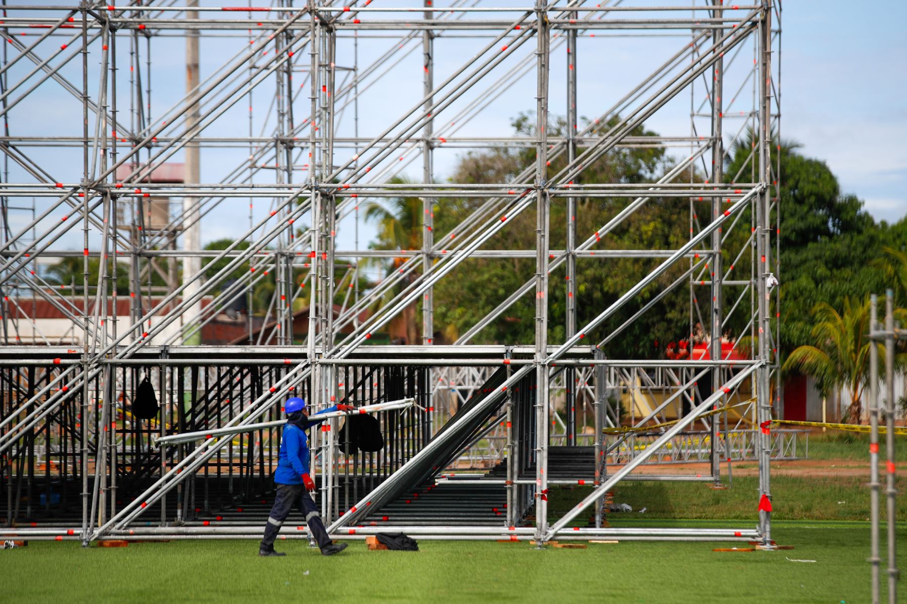 Técnicos equipados con cascos y arneses recorren la explanada del complejo deportivo La Videnita, en Pucallpa, mientras coordinan los trabajos de montaje y supervisan el avance de las estructuras para la misa del papa León XIV. Foto: ANDINA/Ricardo Cuba