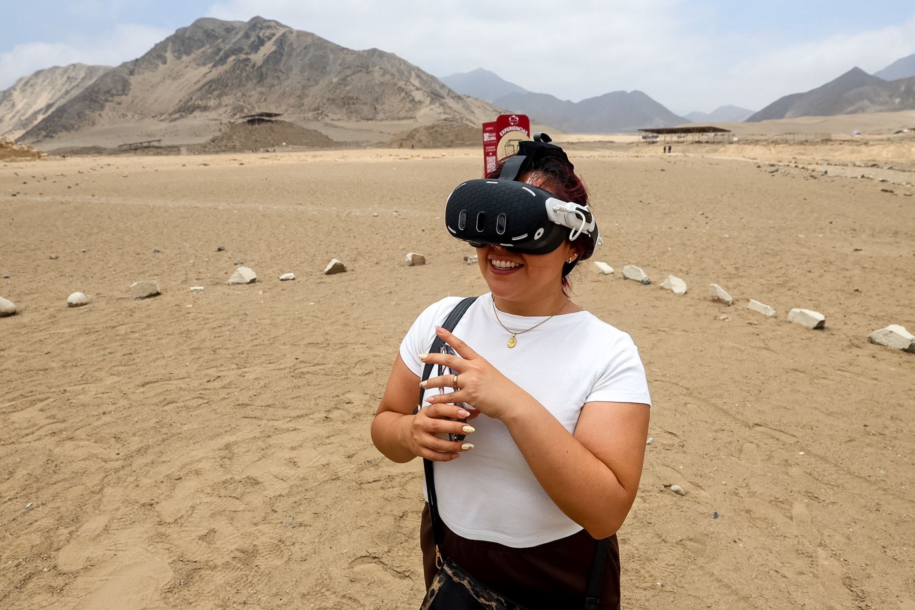 En medio del paisaje desértico de Caral, una visitante utiliza un visor Oculus de realidad virtual para explorar recreaciones de la antigua civilización. Esta experiencia tecnológica permite recorrer virtualmente el Edificio Piramidal Mayor y el Altar de Fuego, acercando al público al patrimonio arqueológico de la civilización más antigua de América. Foto: ANDINA/Luis Iparraguirre.