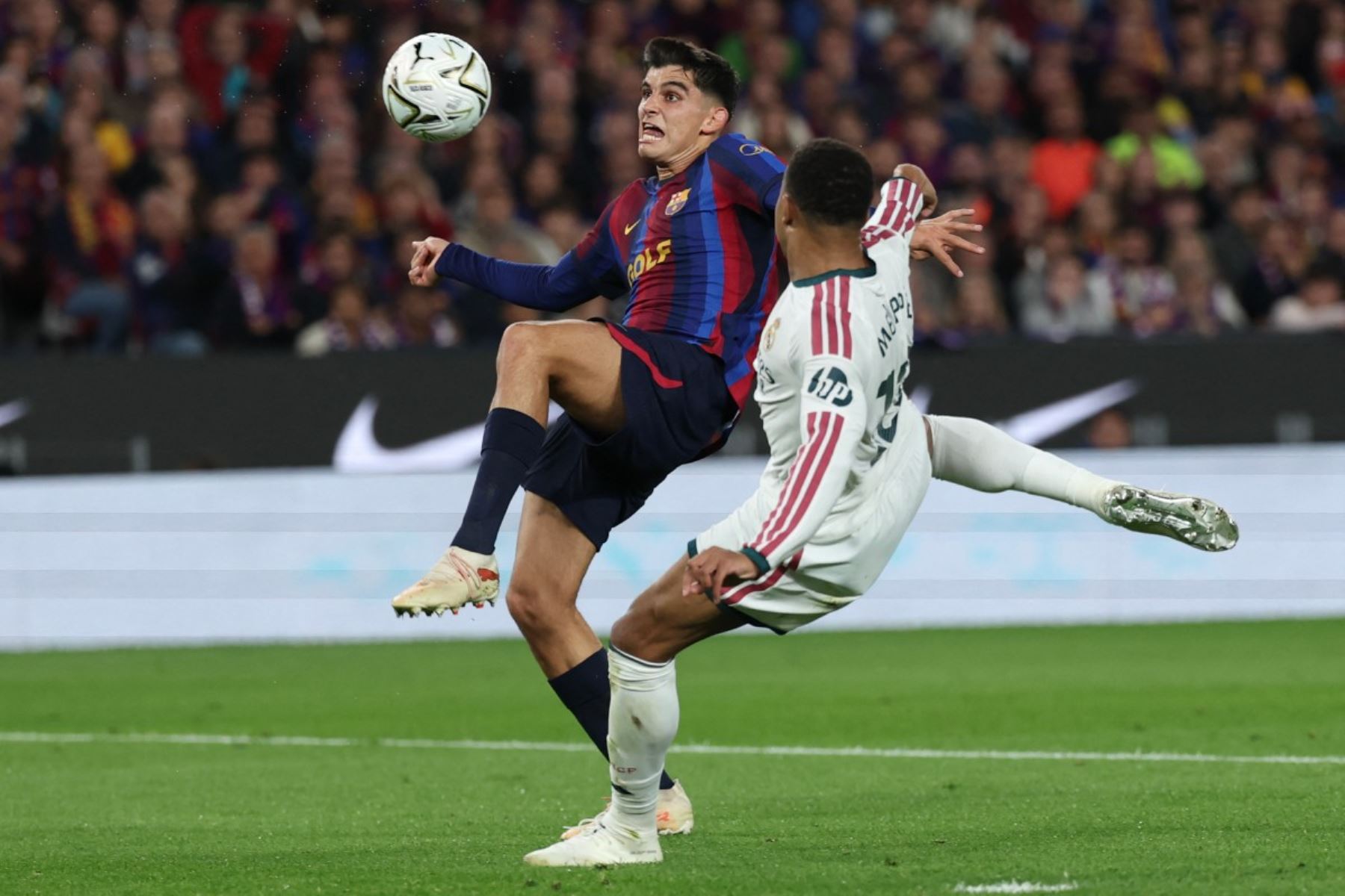 El defensa español del Barcelona, ​​Gerard Martín  disputa un balón con el delantero francés del Real Madrid, Kylian Mbappé  durante el partido de la liga española de fútbol entre el FC Barcelona y el Real Madrid. AFP